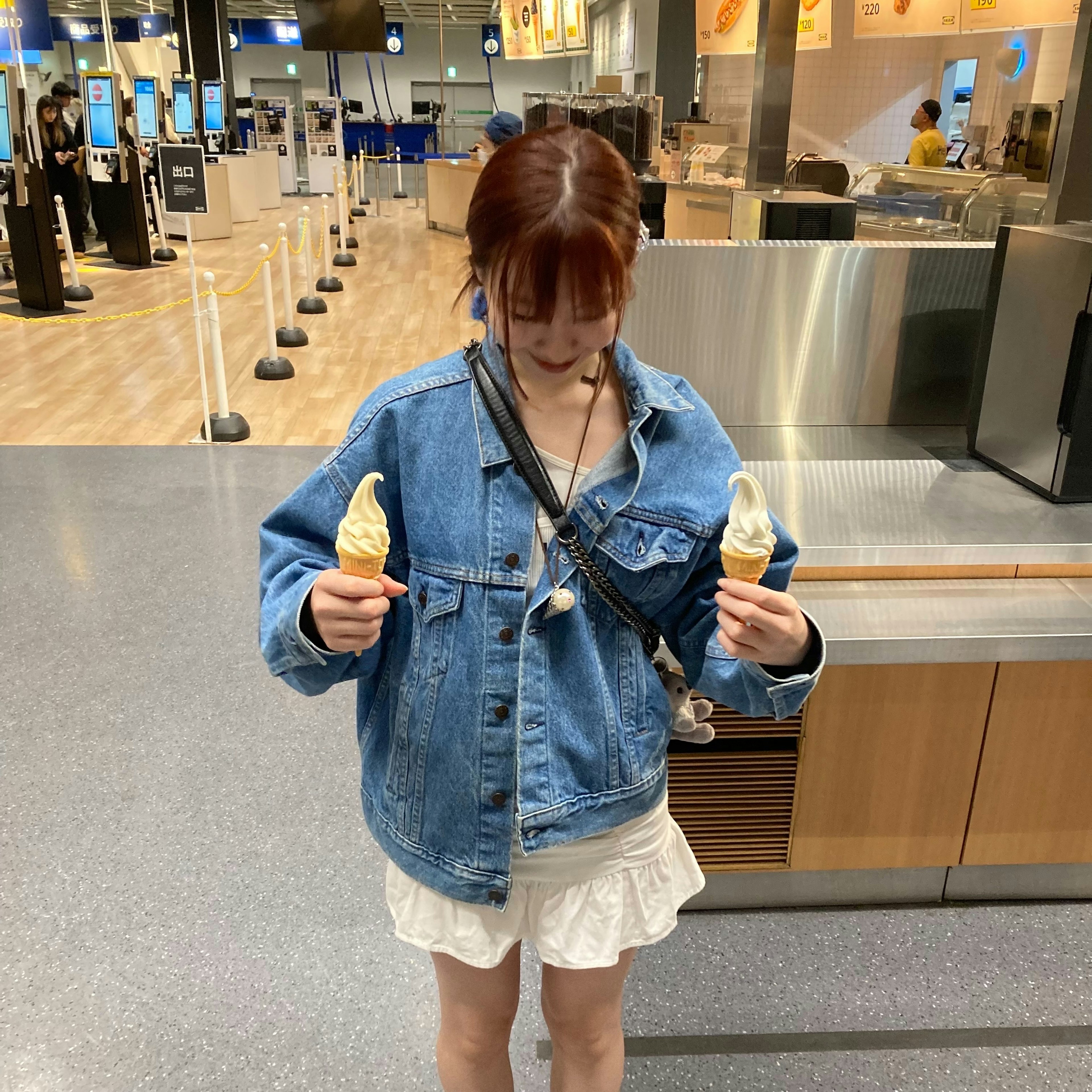 Mujer con chaqueta de mezclilla sosteniendo dos conos de helado en un aeropuerto