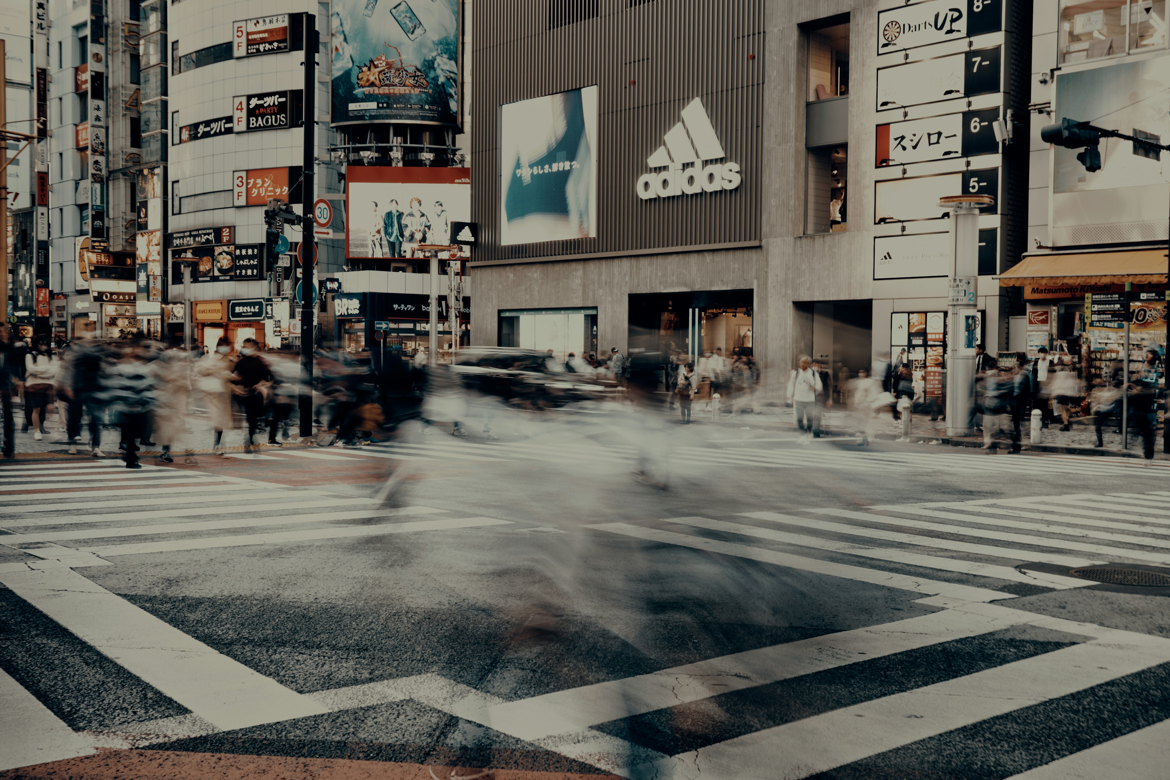 Crowd crossing a street with urban advertisements in the background