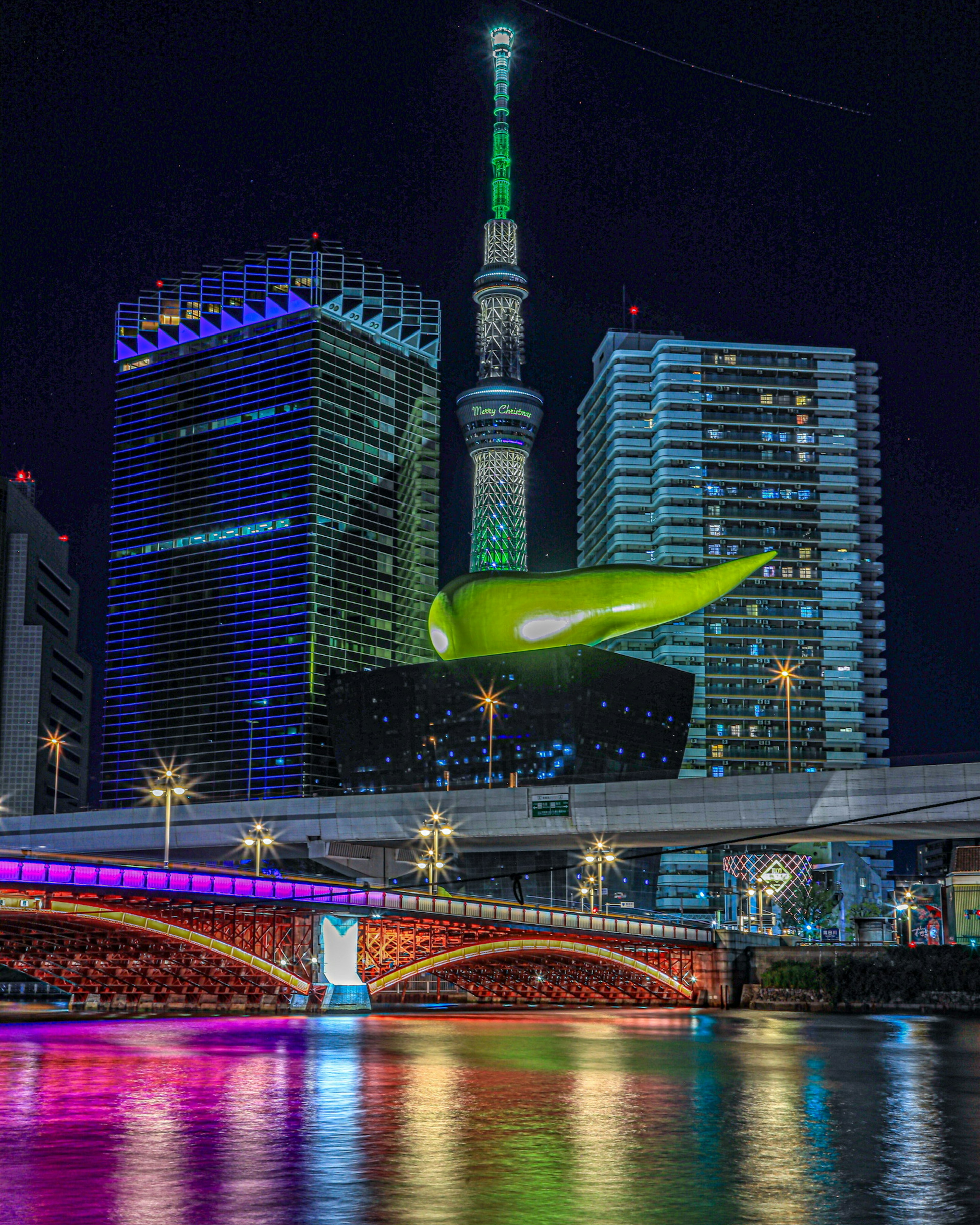 Tokyo Skytree dengan pemandangan malam yang berwarna-warni dan gedung-gedung yang diterangi