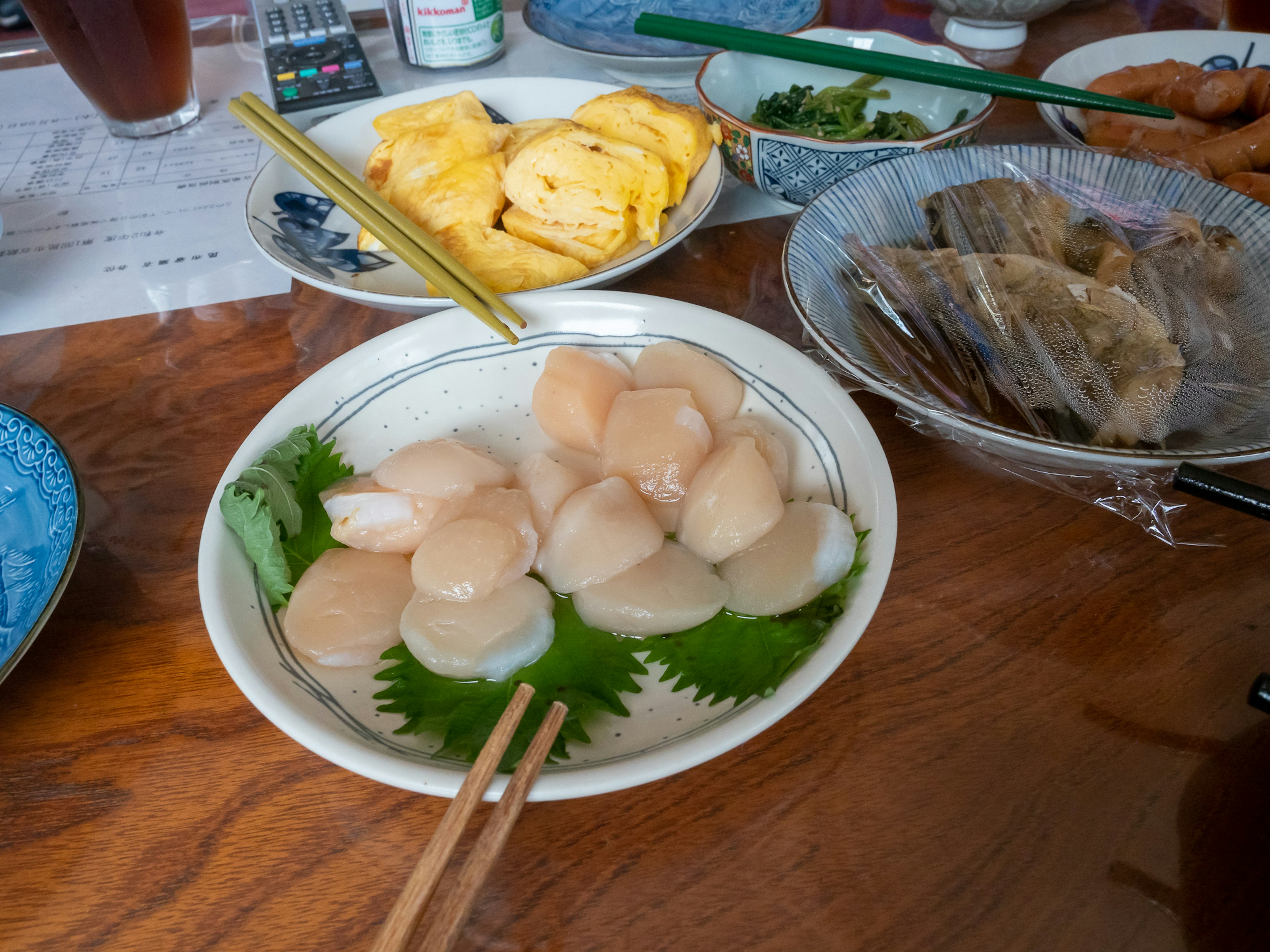 新鮮なホタテの刺身が盛り付けられた皿と周囲の料理