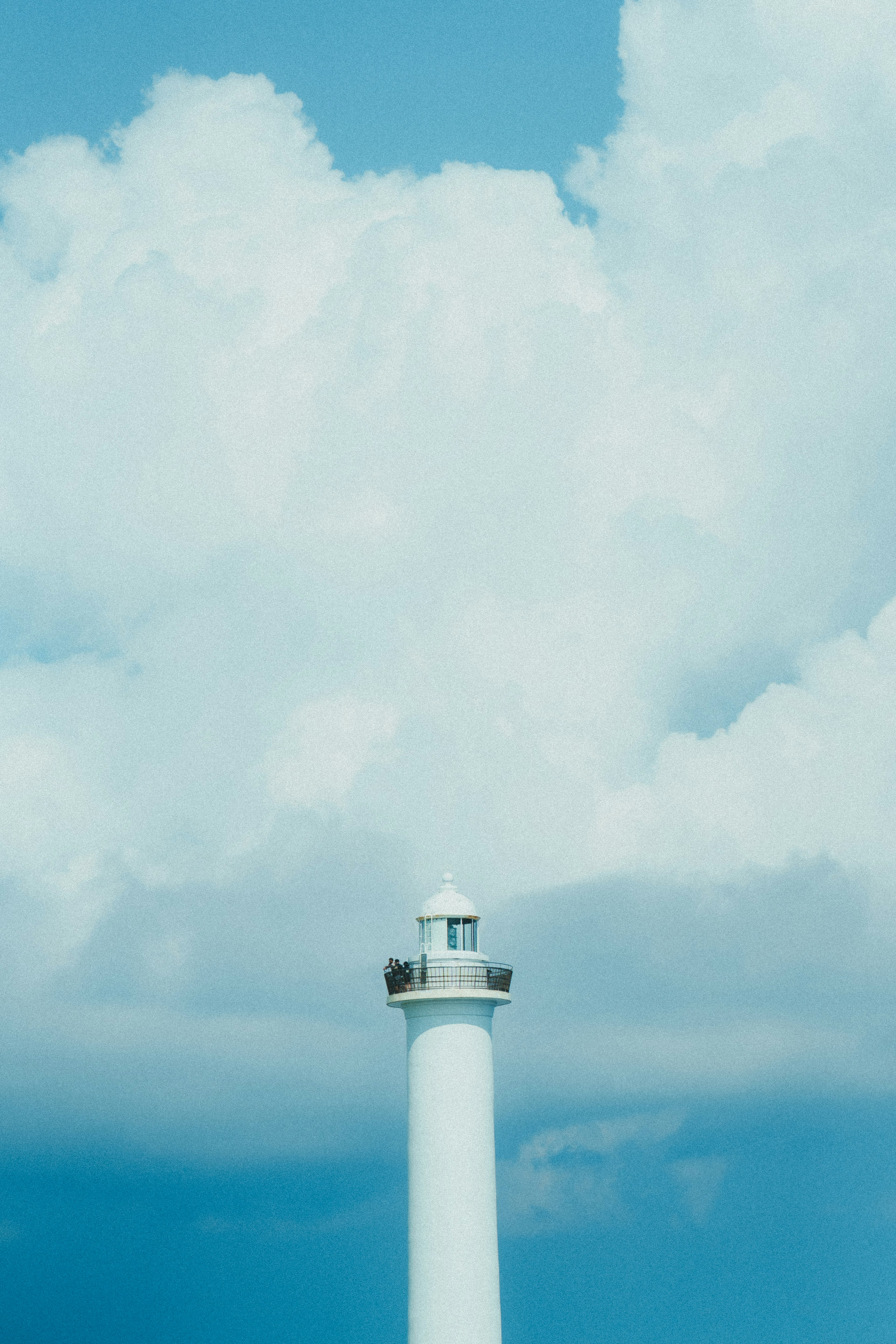 Bild eines Leuchtturms vor blauem Himmel und weißen Wolken