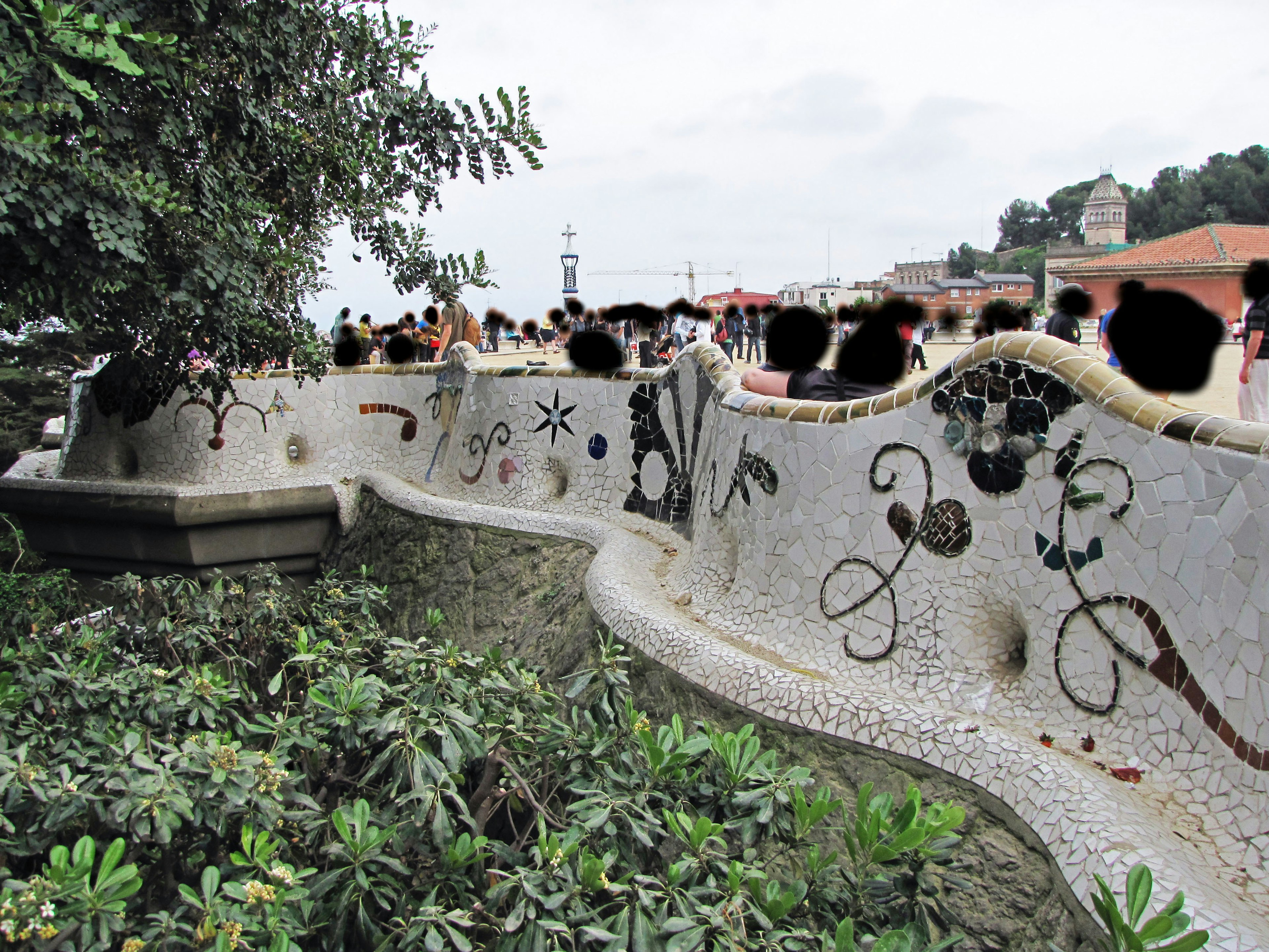 Mosaikbank mit umgebender Vegetation und Menschen im Hintergrund