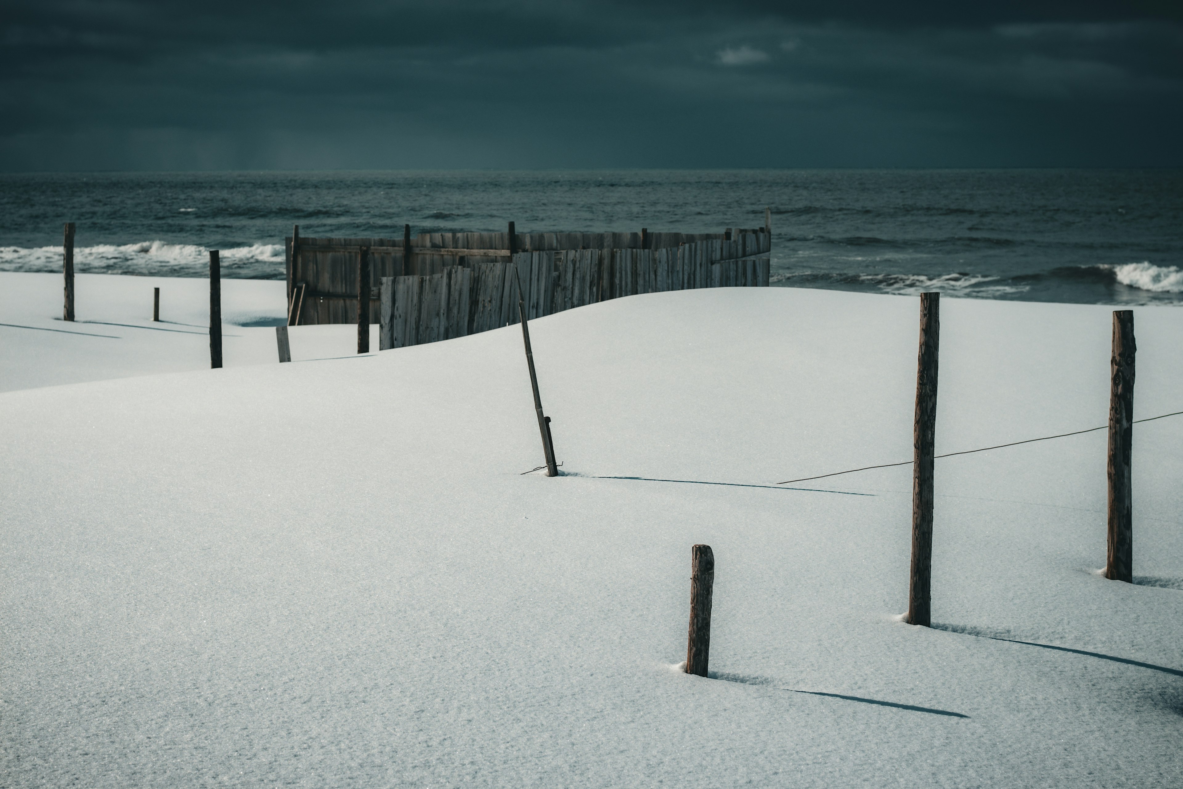 Un paesaggio con un molo di legno sulla riva e dune di sabbia