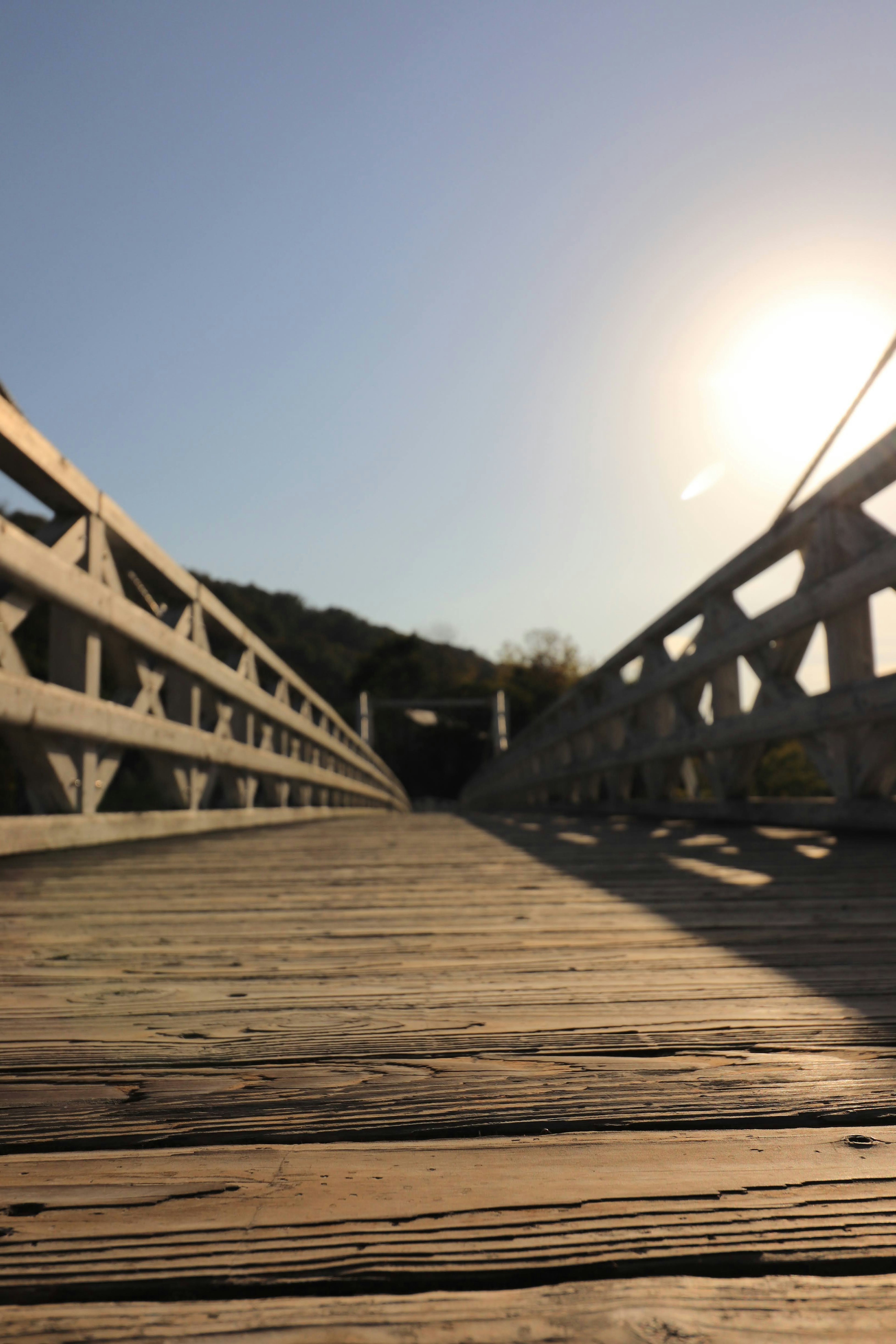 Holzbrücke, die sich unter blauem Himmel und Sonnenlicht erstreckt