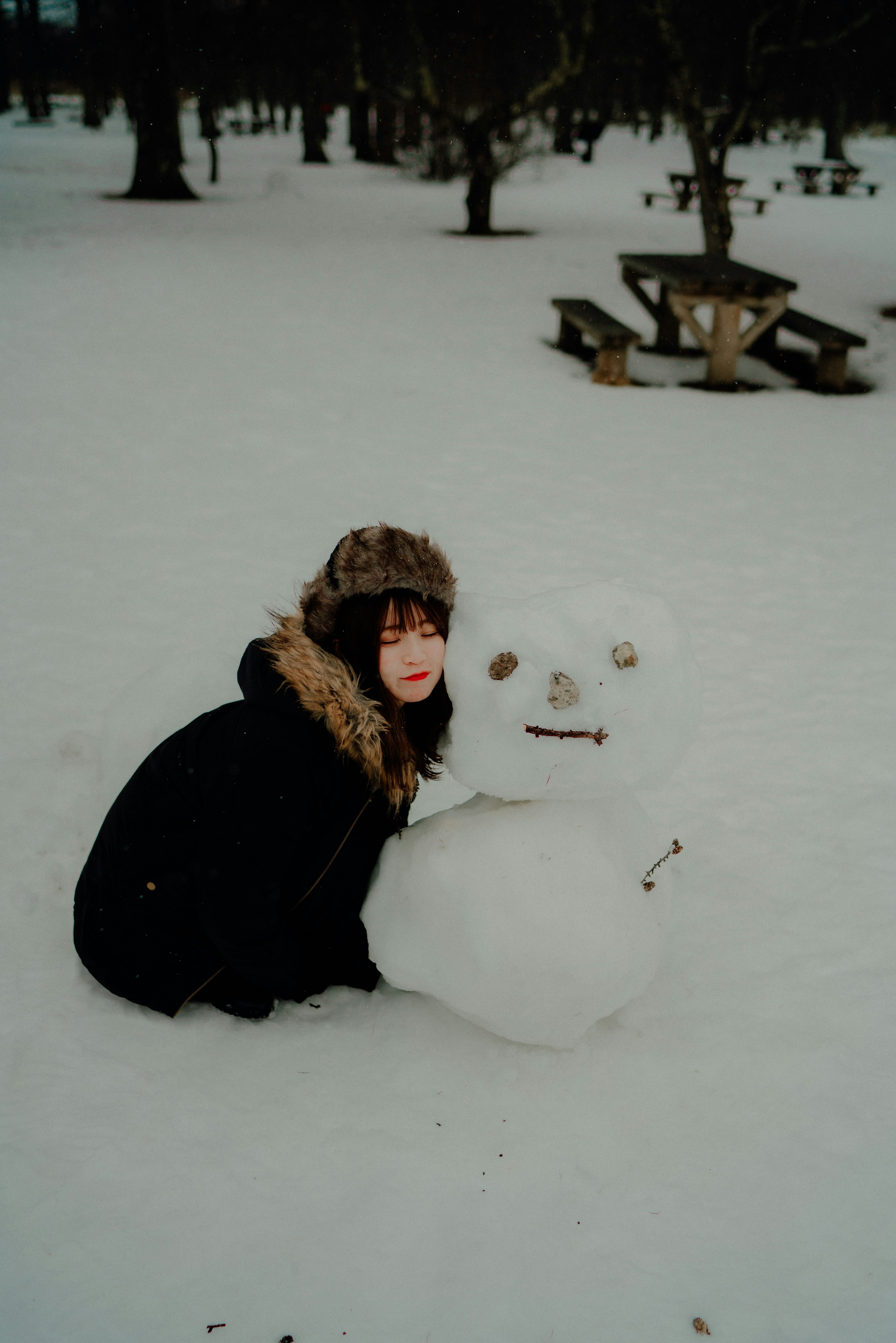 雪の中に座っている女性と雪だるま