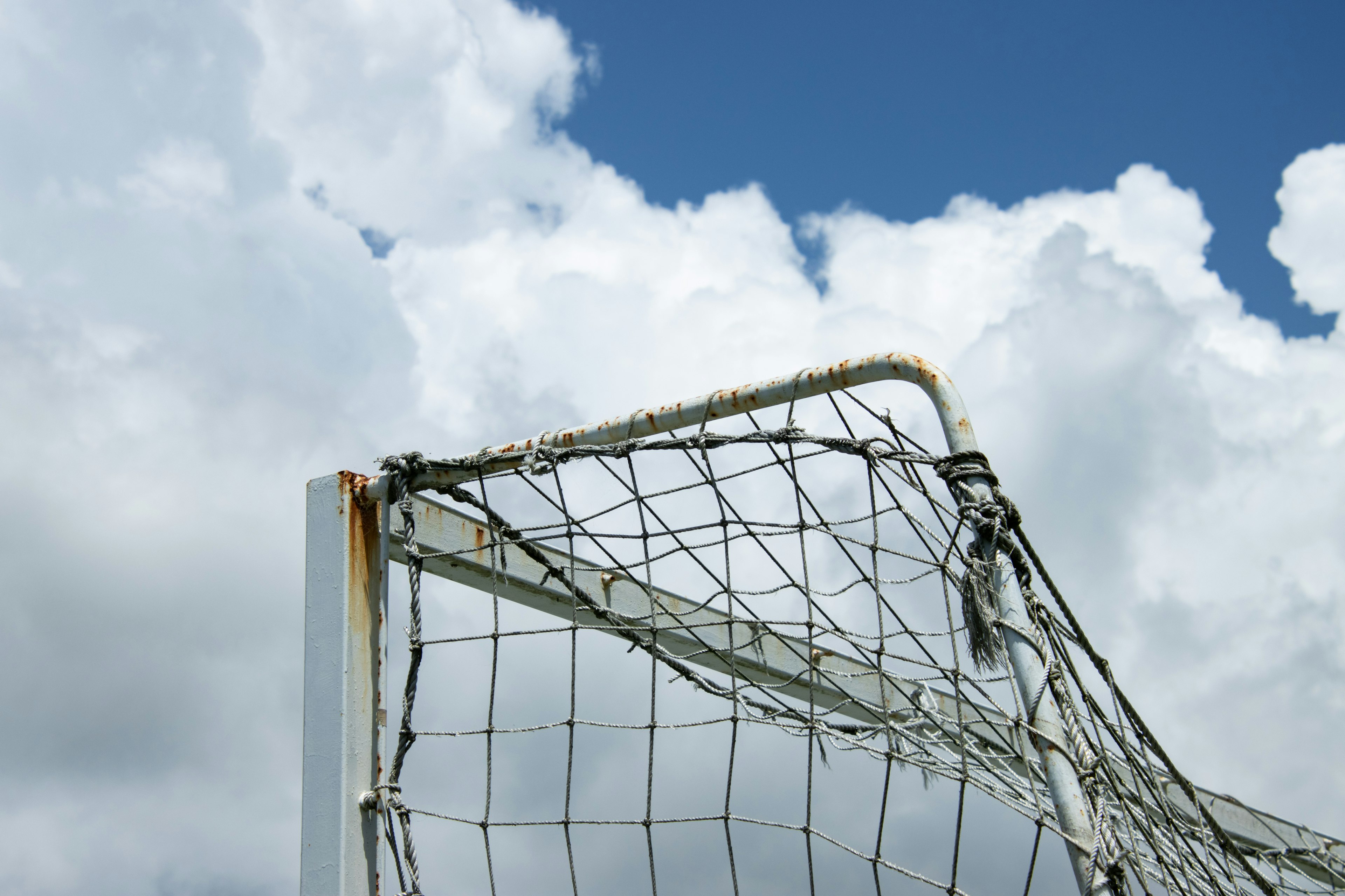 Close-up of a soccer goal net against a blue sky