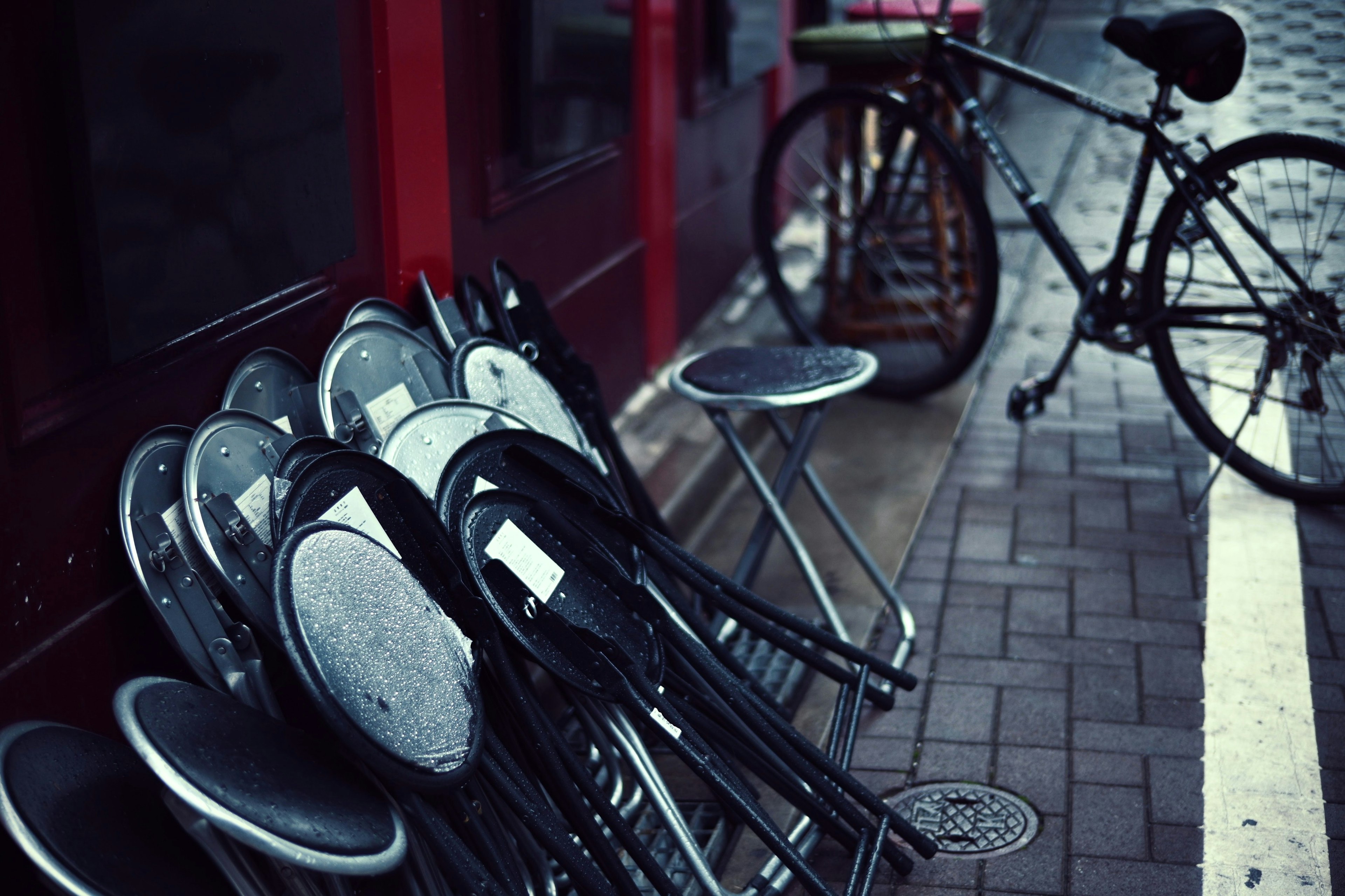 Eine Szene mit gestapelten schwarzen Stühlen und einem Fahrrad auf dem Bürgersteig