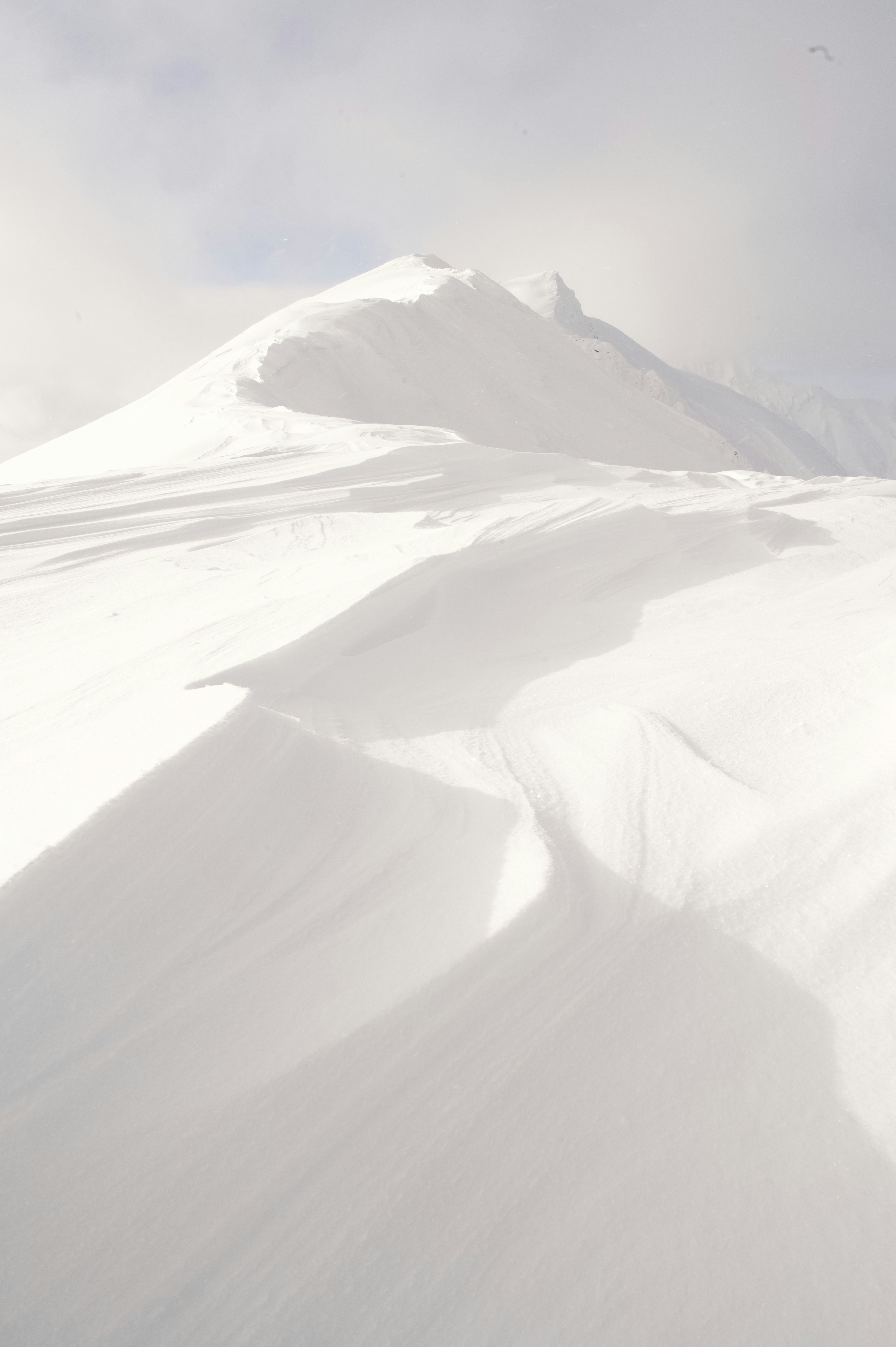 Schneebedeckte Berghang mit sanften Kurven und Schatten