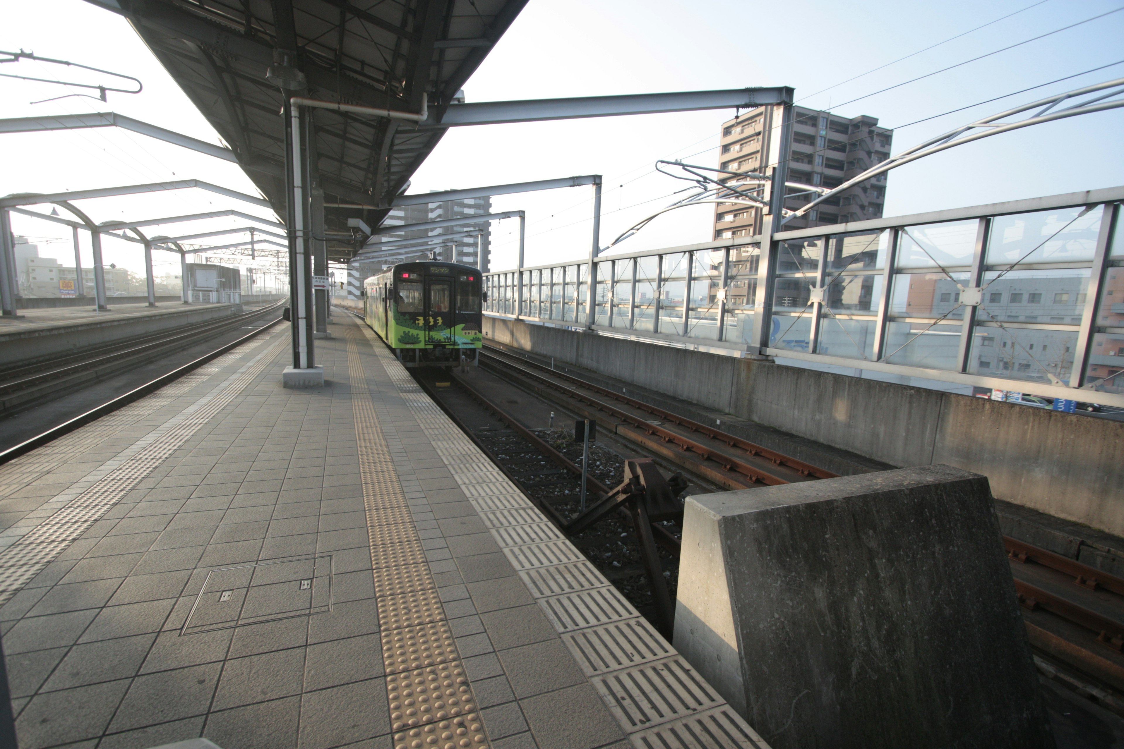 駅のプラットフォームに停車中の電車と周囲の建物