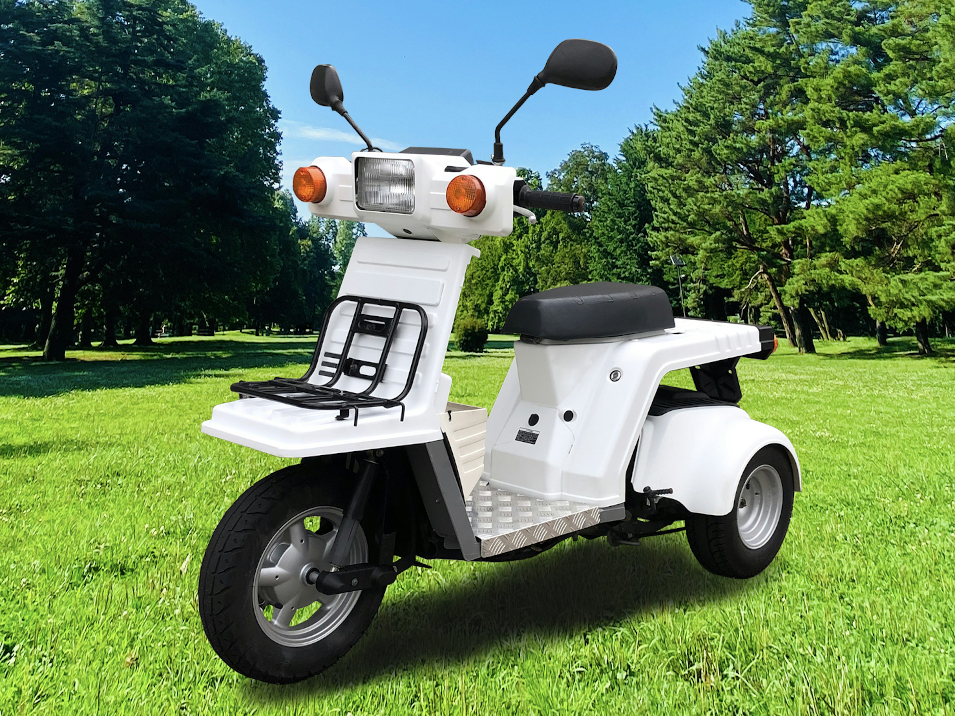 A white three-wheeled scooter parked on green grass