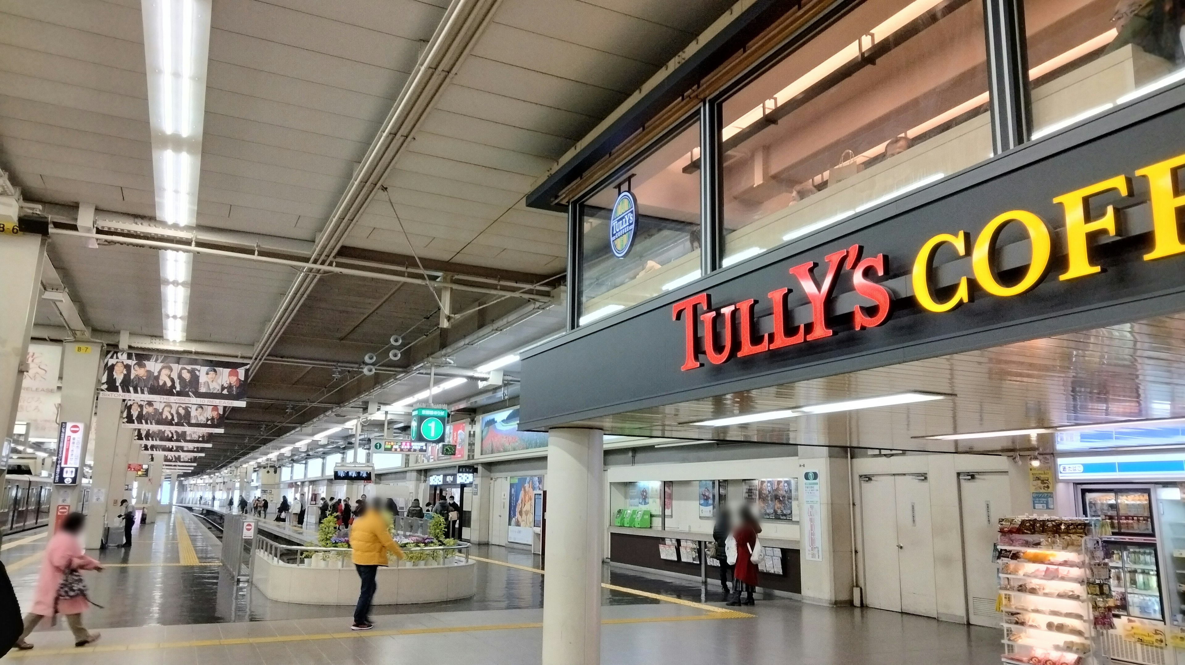 Interior view of a station featuring a Tully's Coffee sign with passengers walking