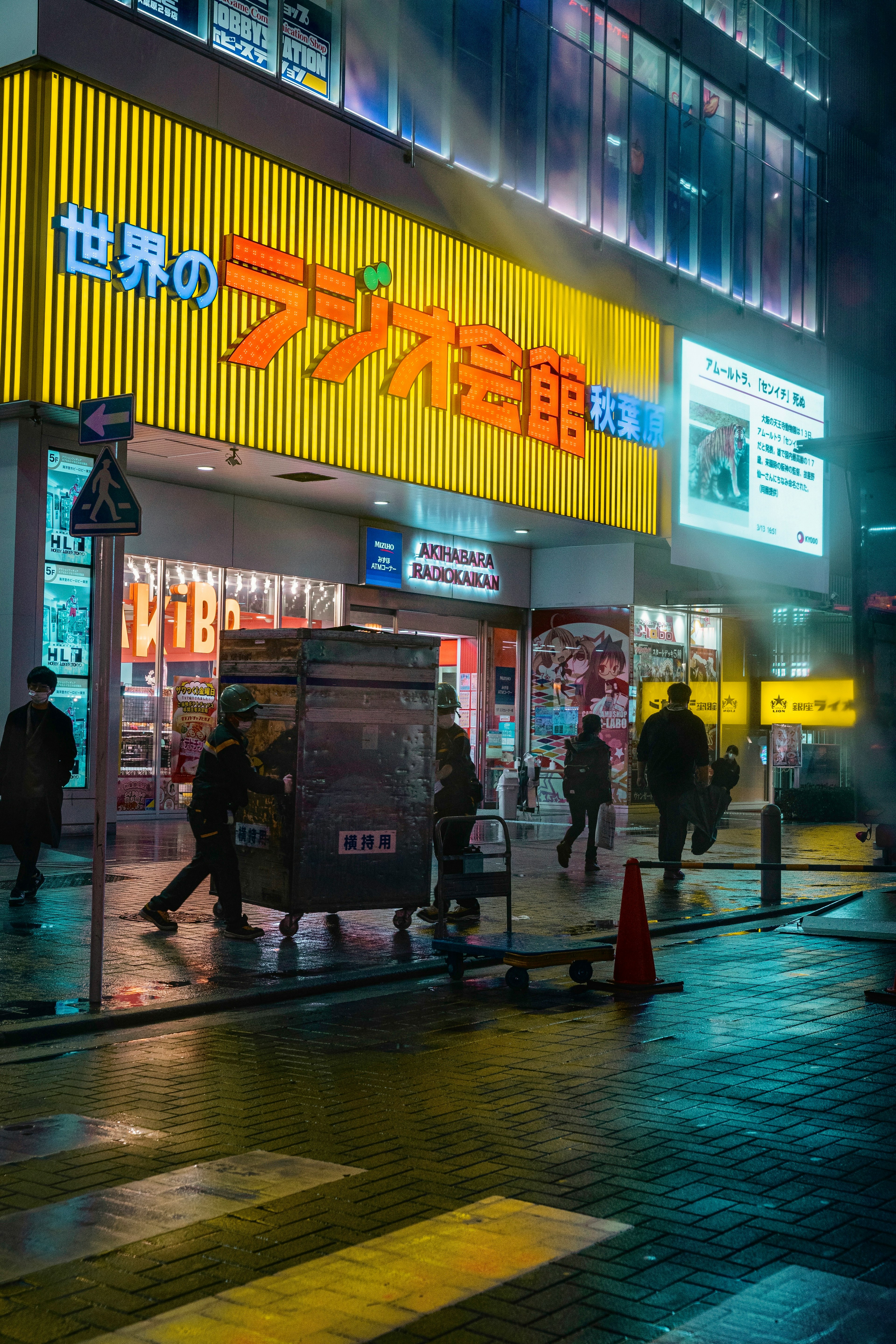 Negozio luminoso con insegna colorata e pedoni in un ambiente urbano notturno