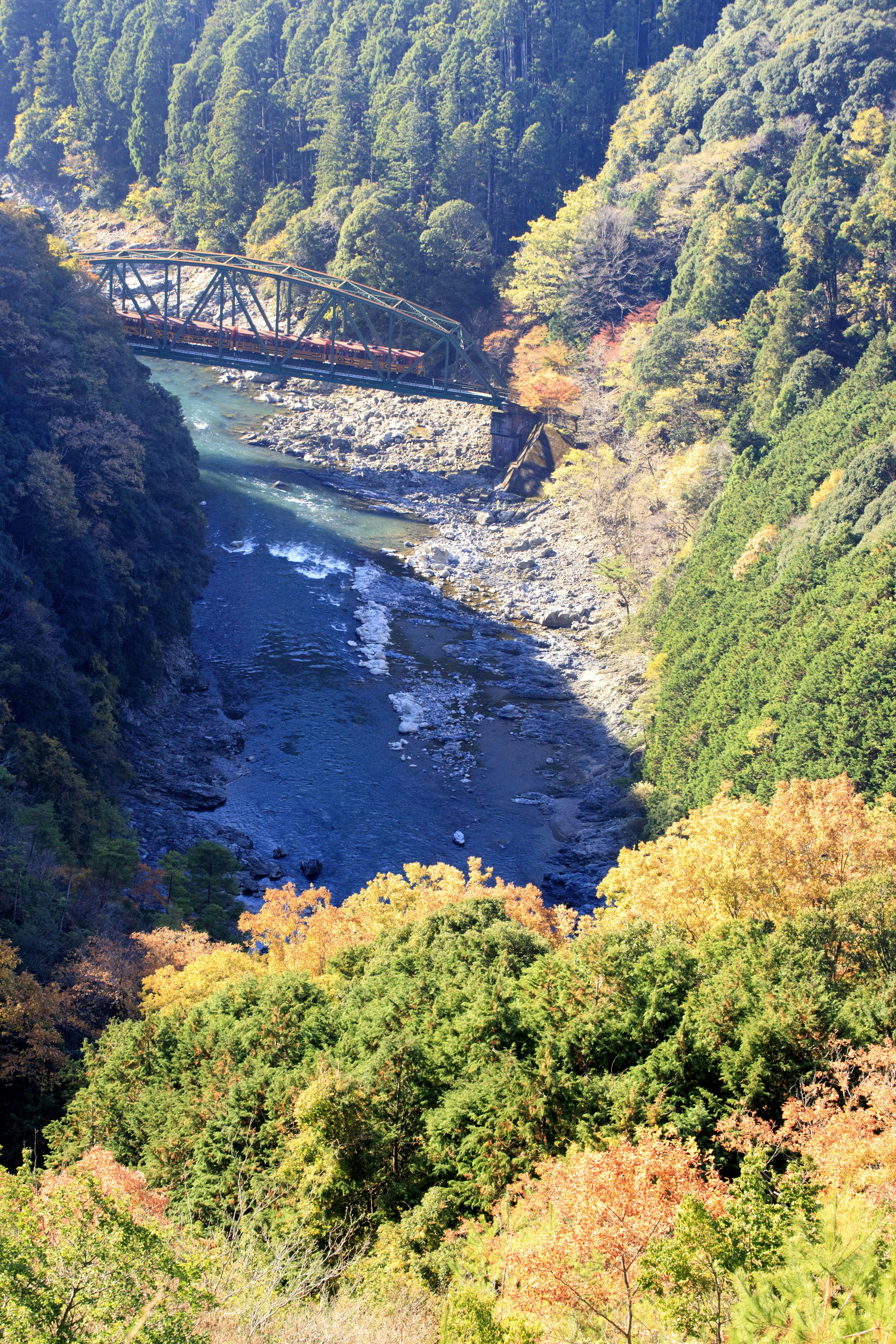 Malersiche Aussicht auf ein Flusstal mit herbstlichem Laub und einer Eisenbahnbrücke