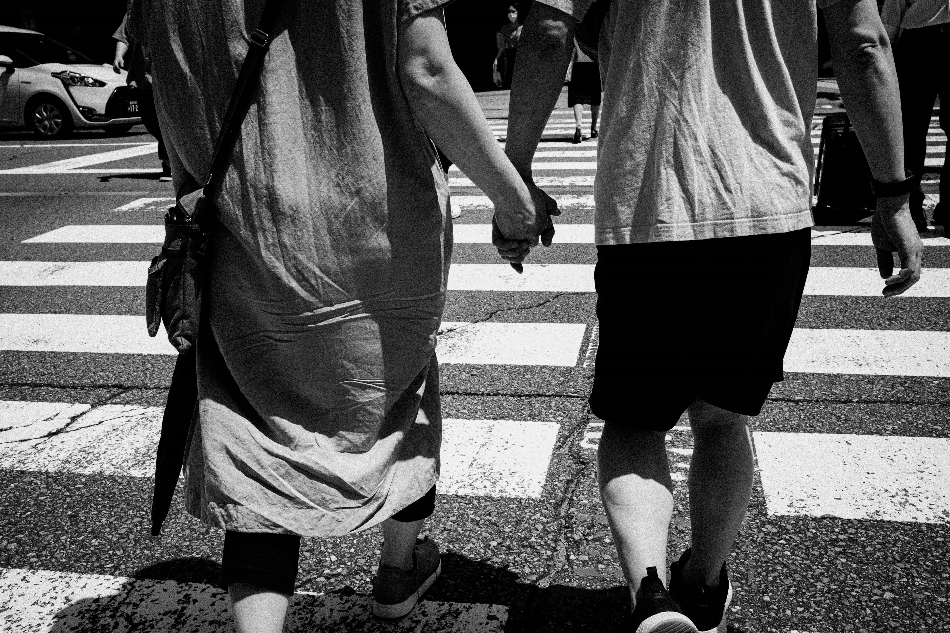 Couple holding hands walking across a crosswalk in black and white