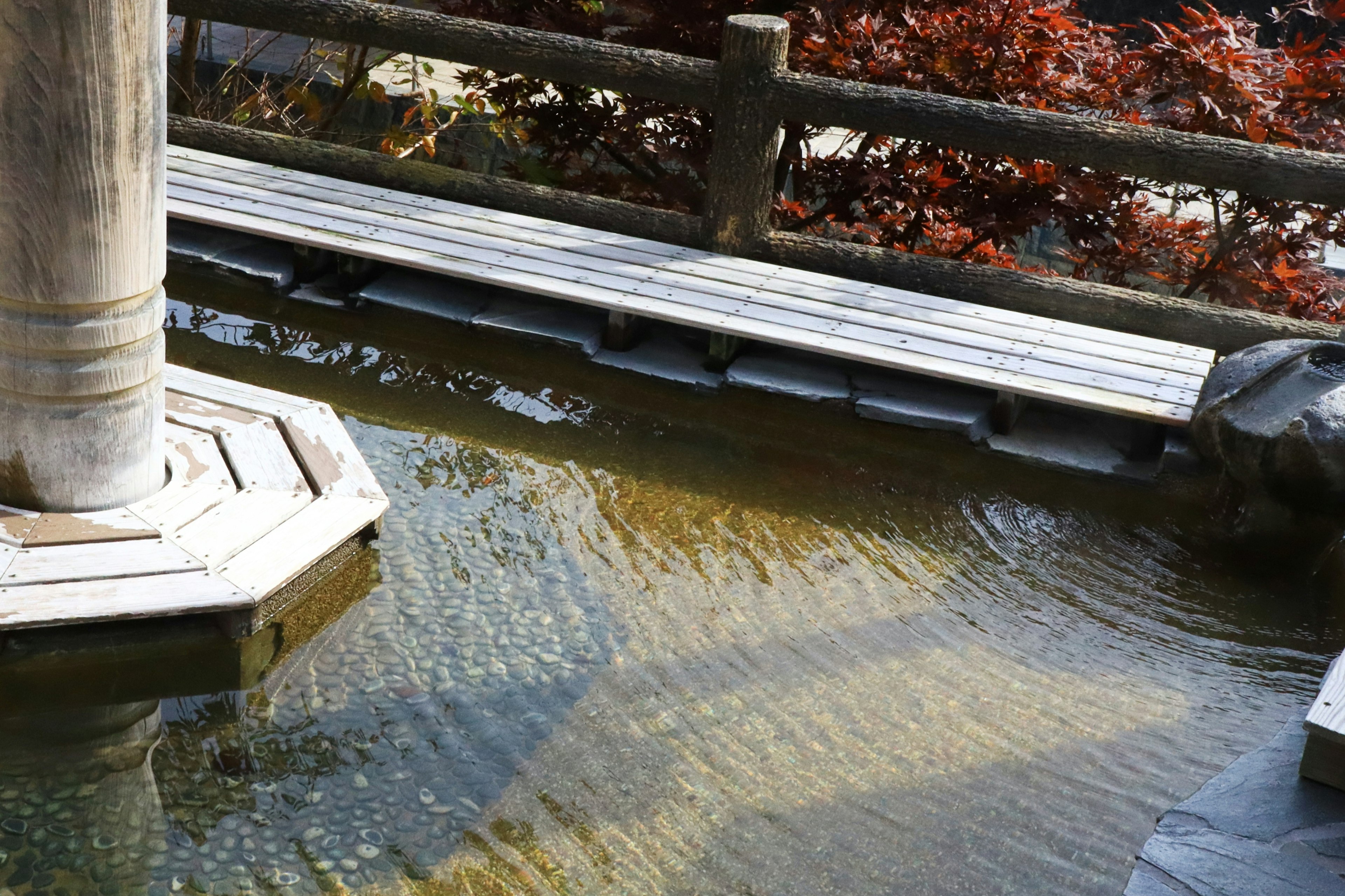 Kolam tenang dengan jalan kayu di taman Jepang