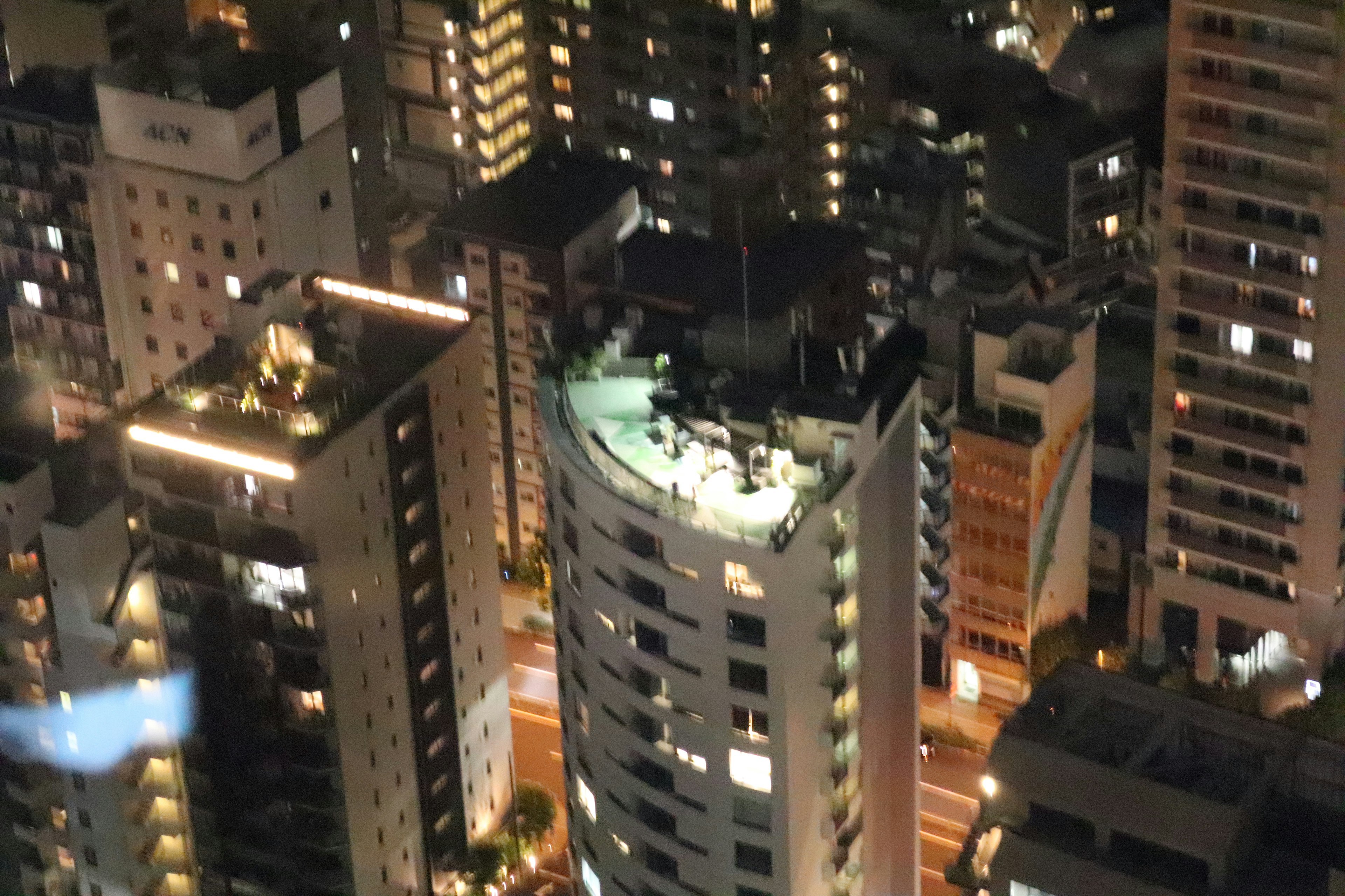 夜景の高層ビル群の中にある丸いビルの屋上