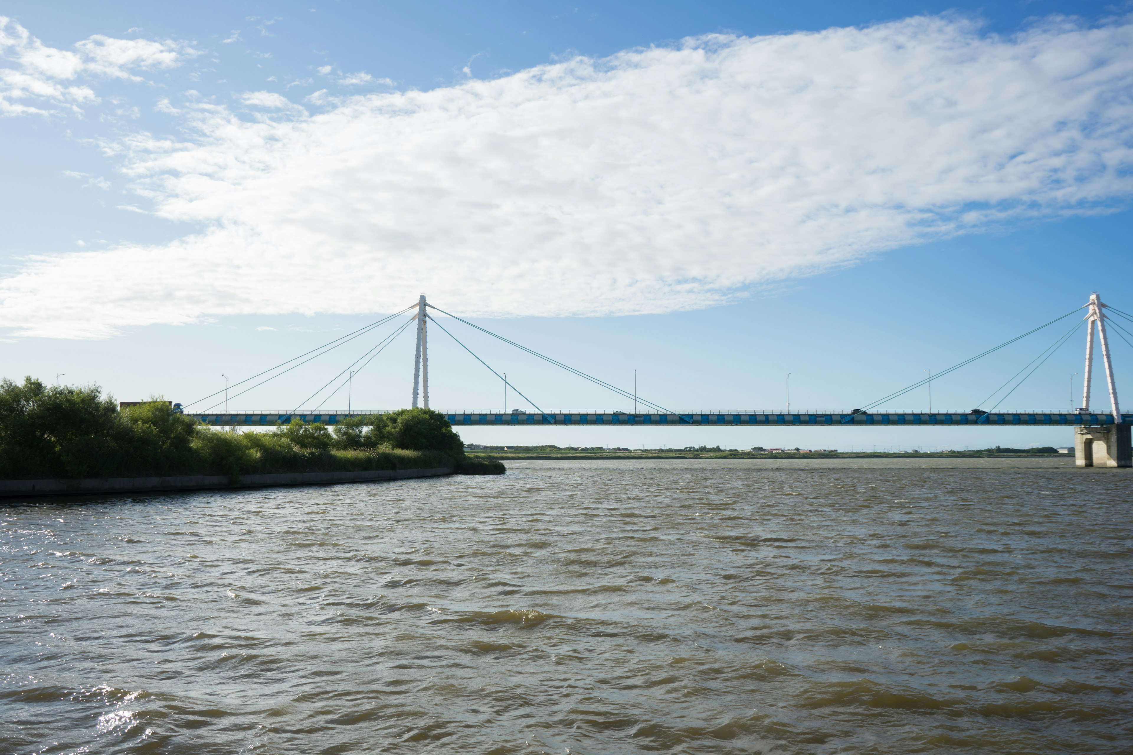 View of a river and suspension bridge under a blue sky