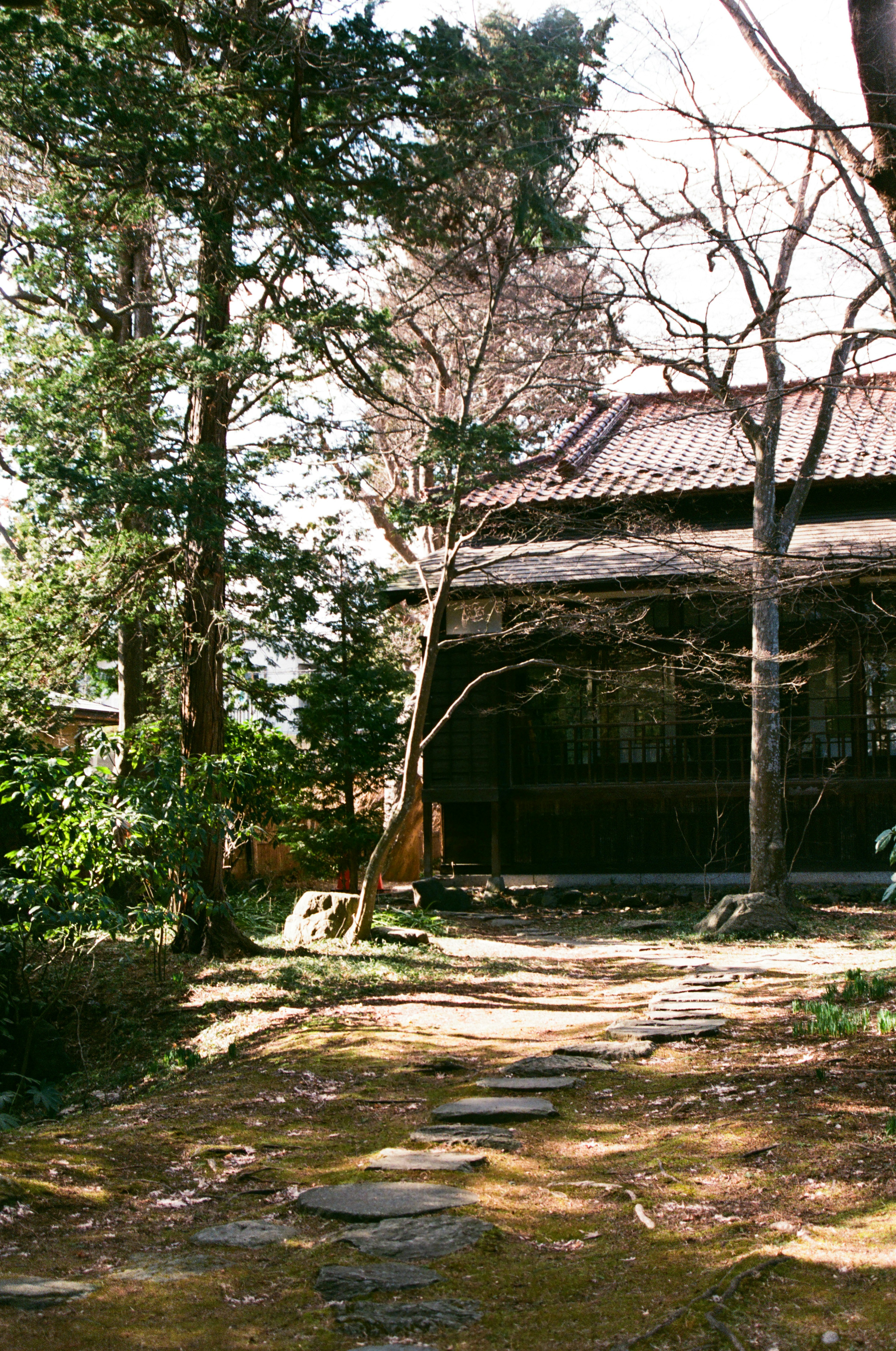 Ein Steinweg in einem Garten mit einem alten japanischen Haus im Hintergrund