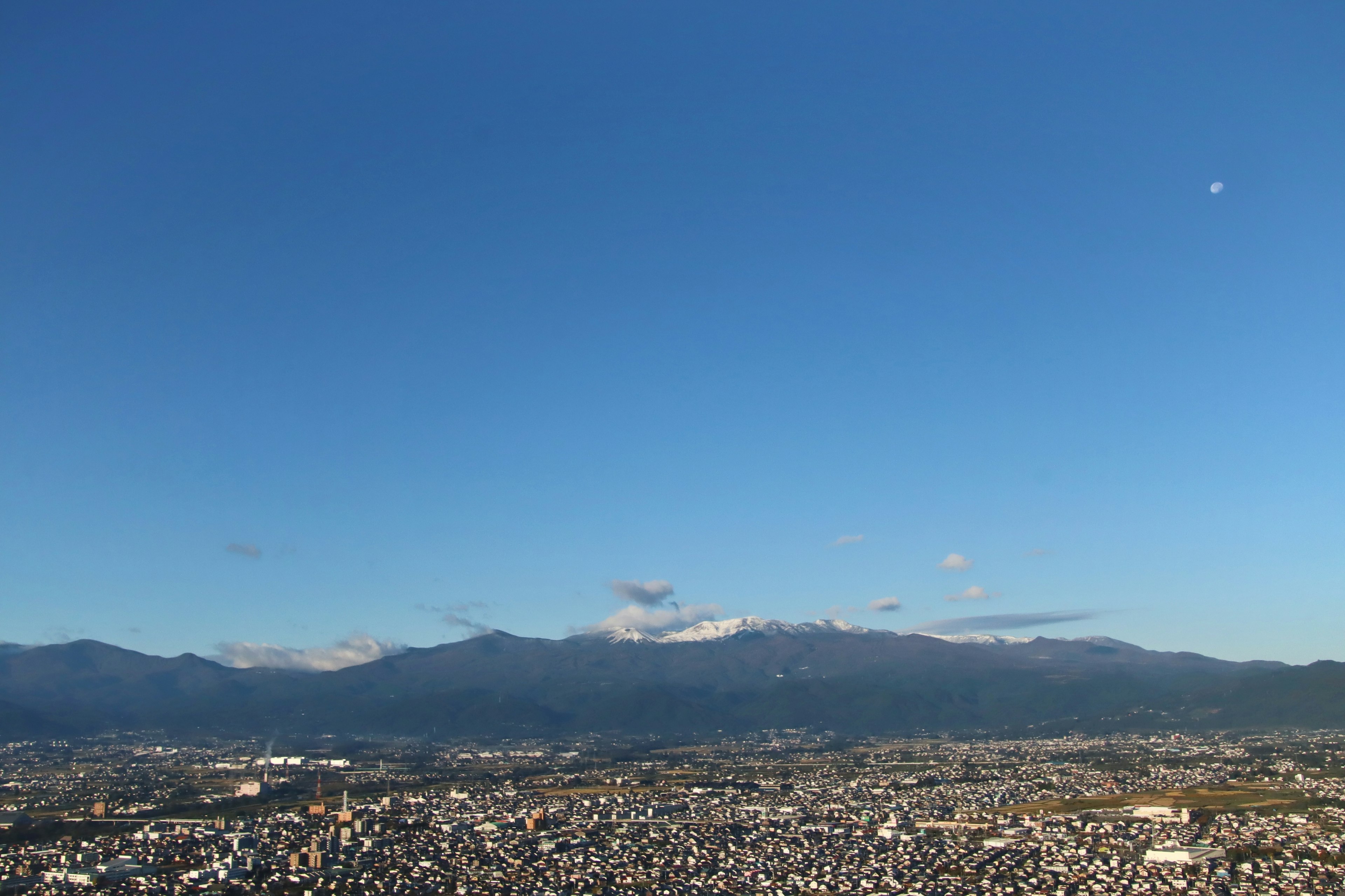 青空の下に広がる都市と遠くの山々の景色