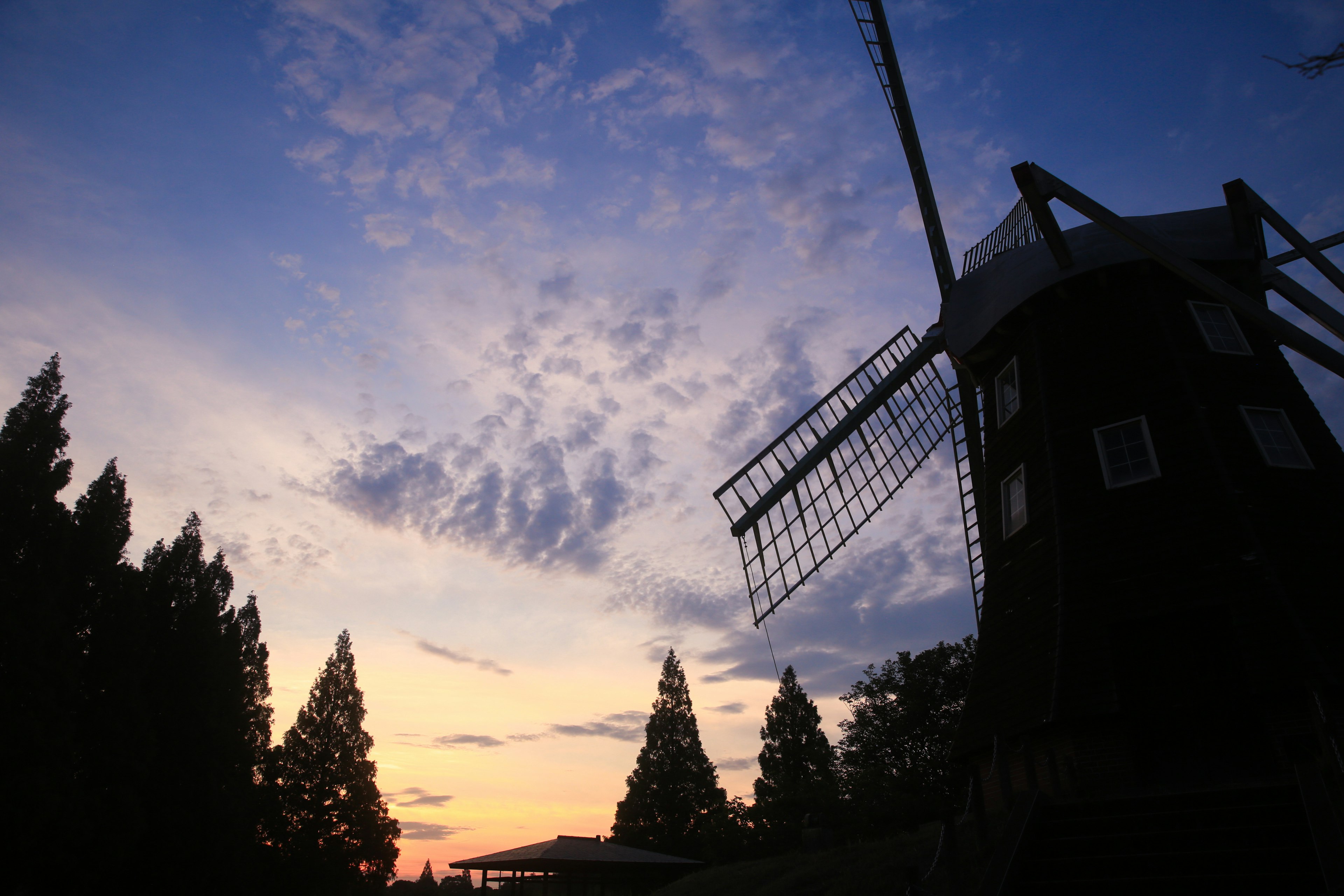 Silhouette of a windmill against a colorful sunset sky