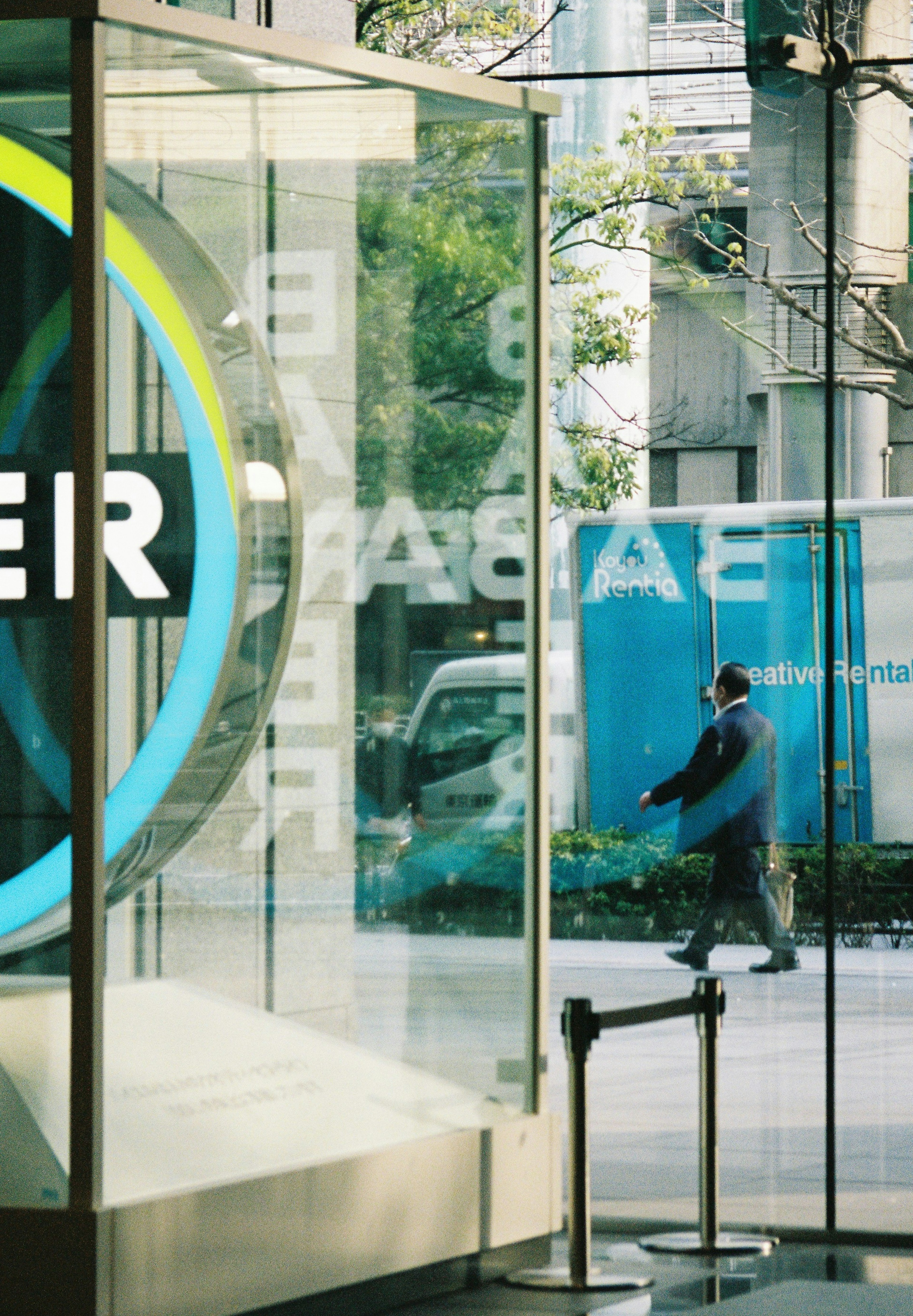 Glass entrance with a blue sign and a person walking outside