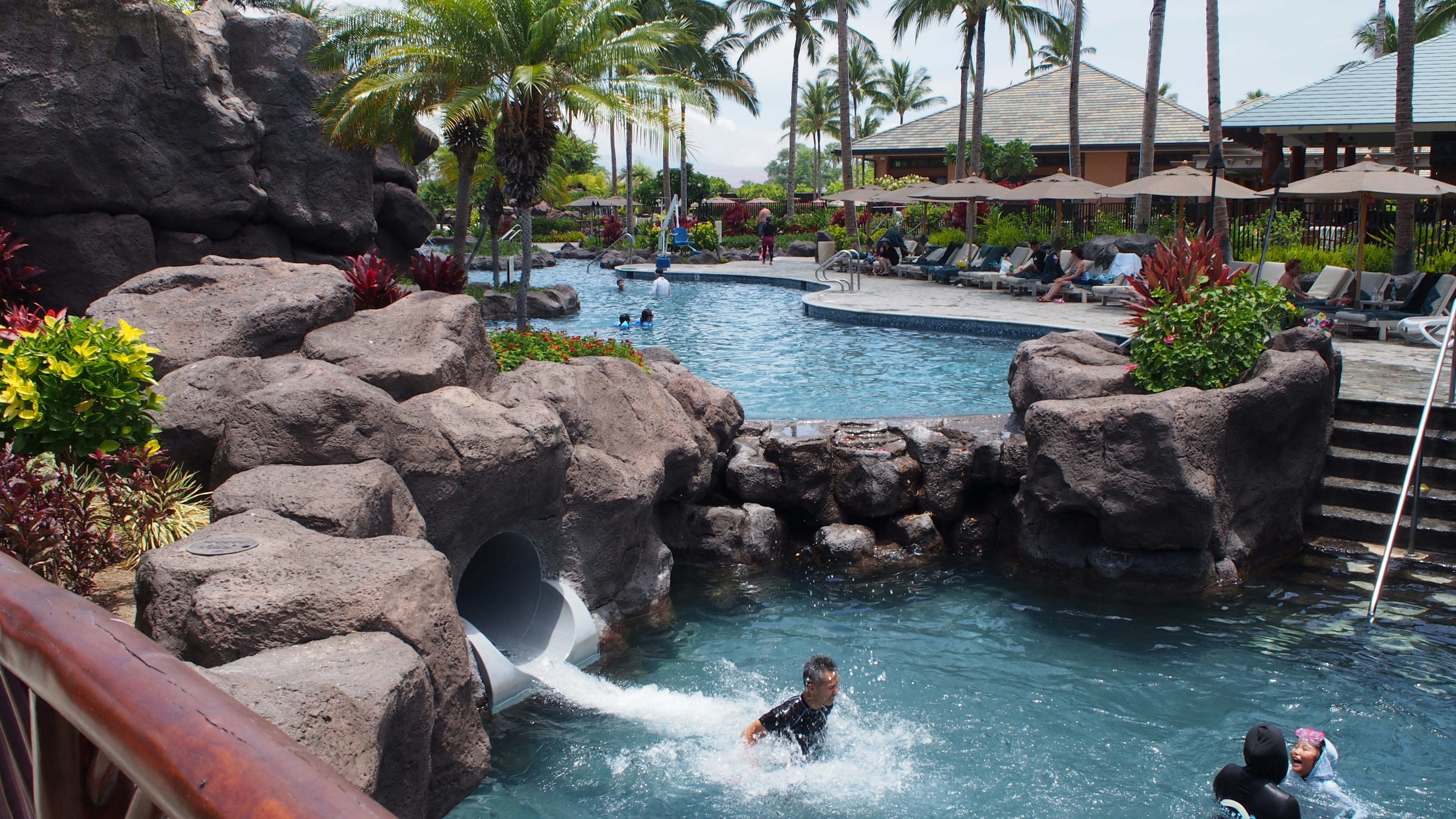 Resort scene with a blue pool and rock slide