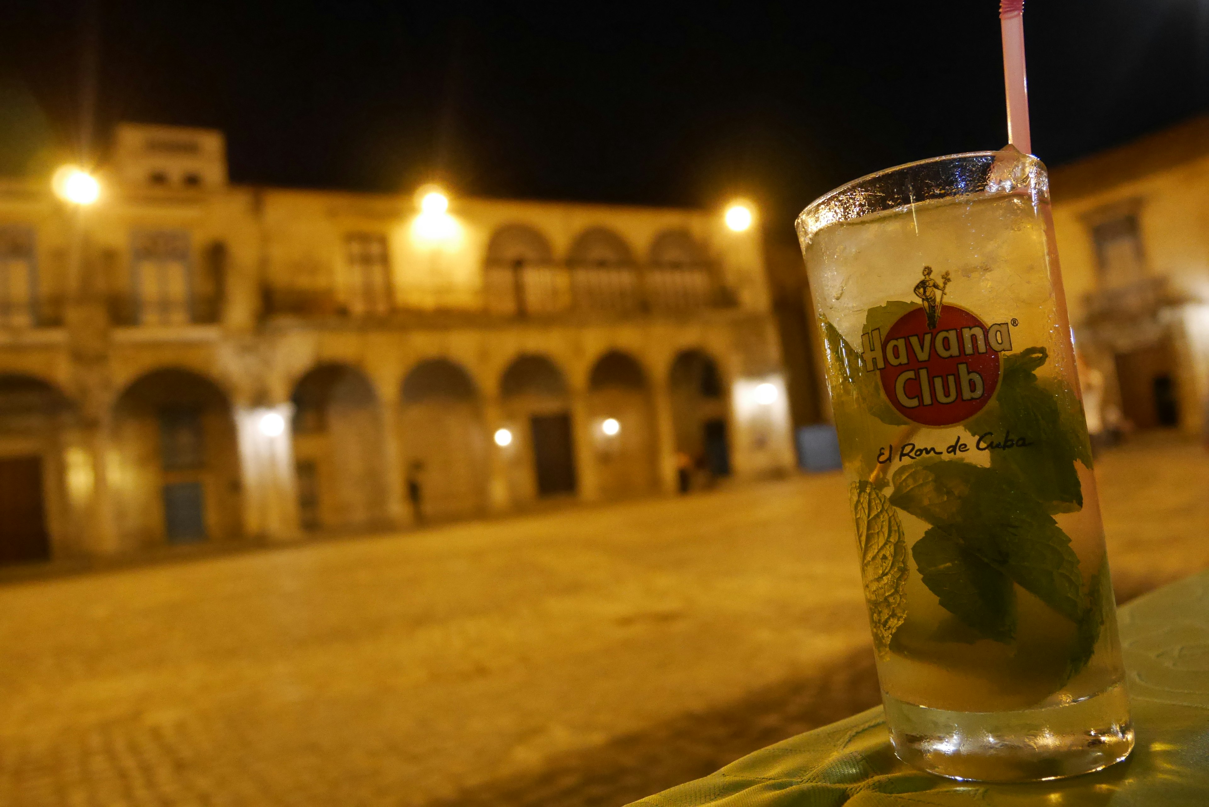 Mojito drink in a glass with mint on a table at night in a plaza