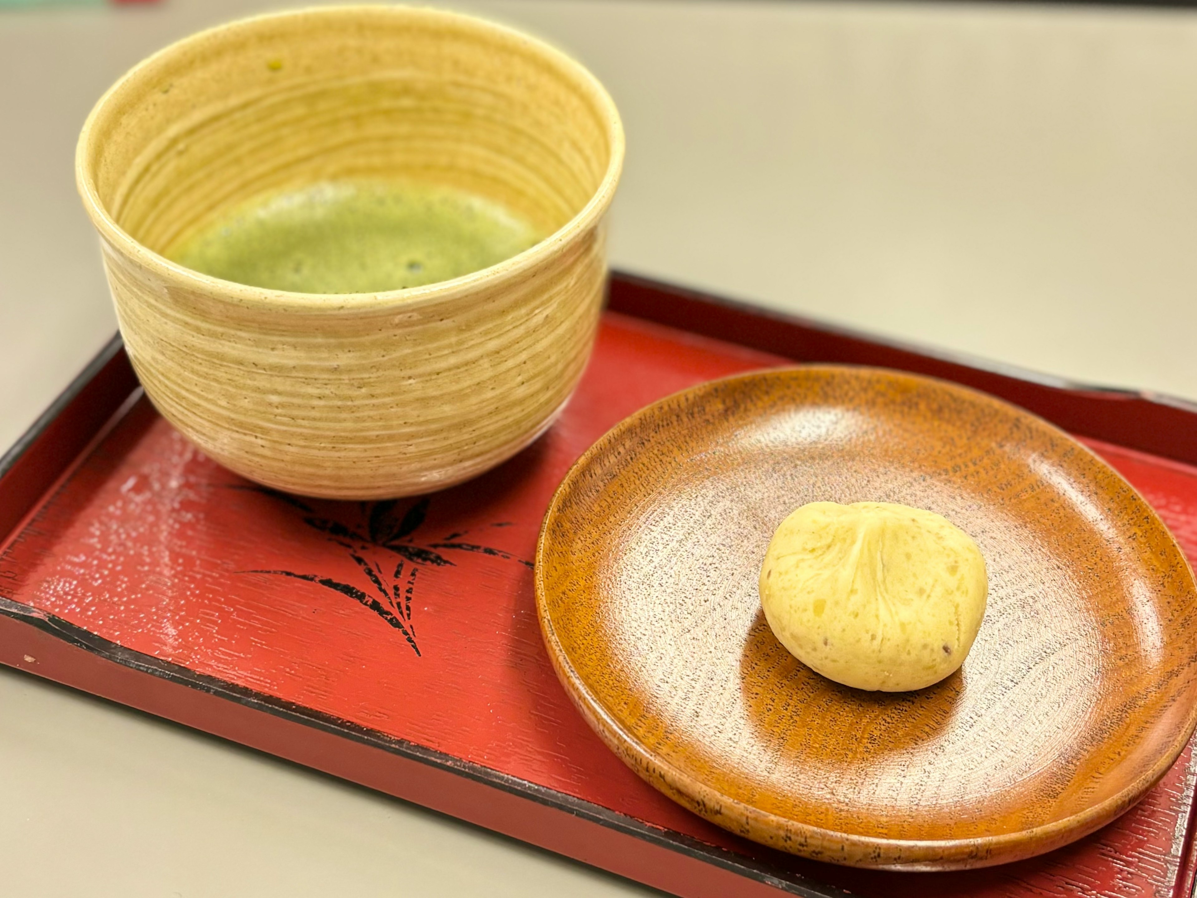 緑茶の茶碗と焼き菓子が置かれた赤いトレイ