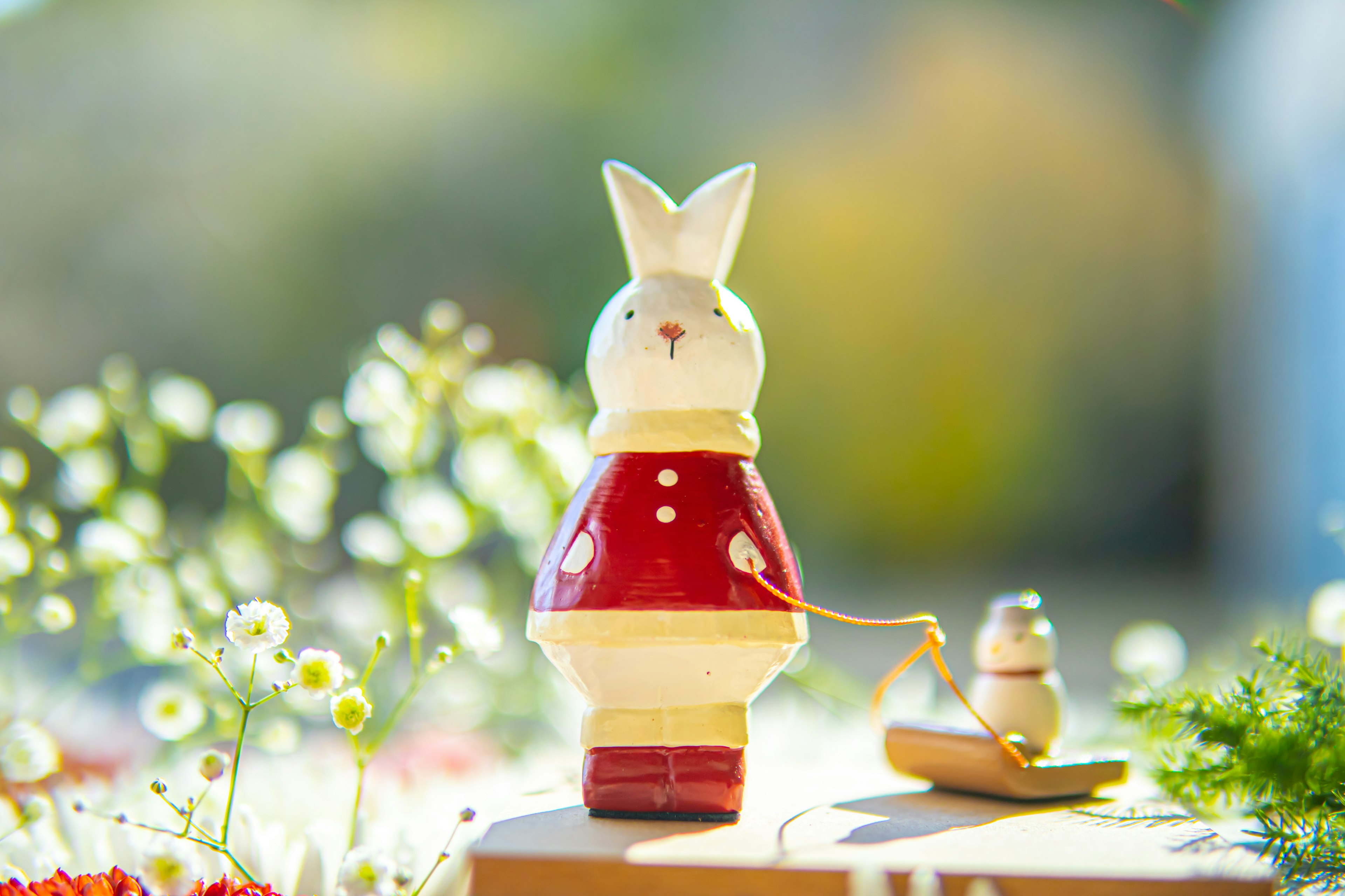 Wooden decoration of a white rabbit wearing a red outfit with a small rabbit beside it