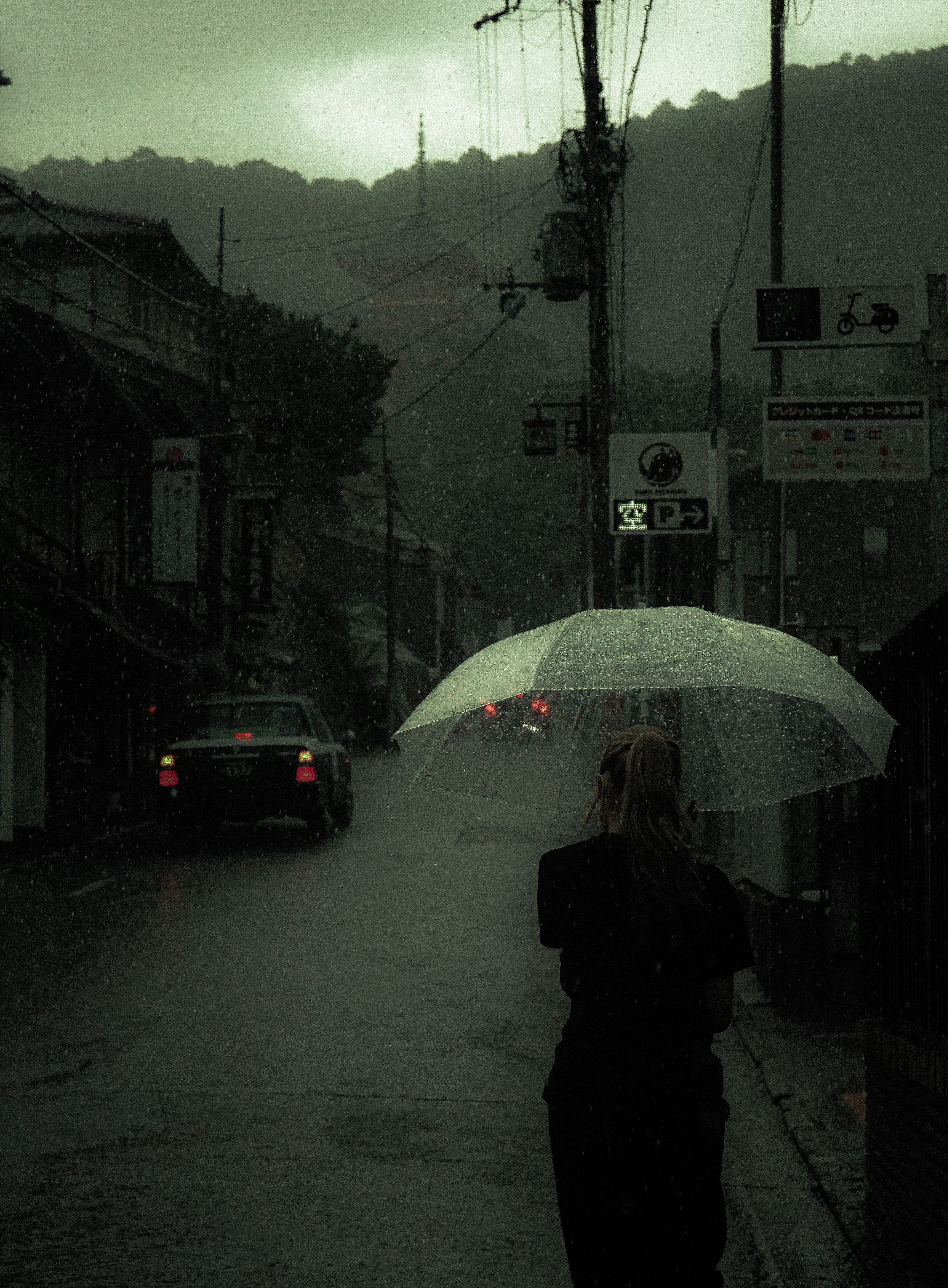 Person holding an umbrella in the rain with a dimly lit street