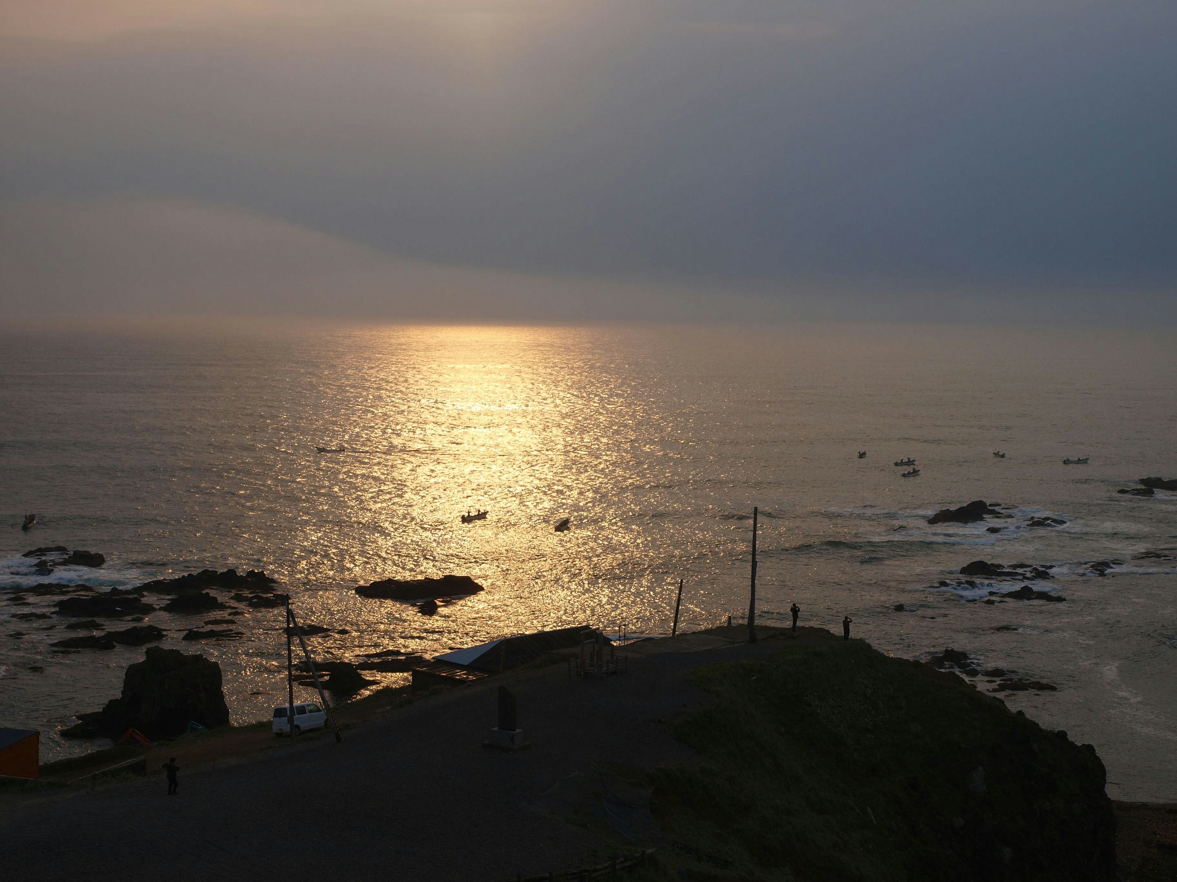 Atardecer costero con olas suaves y costa rocosa