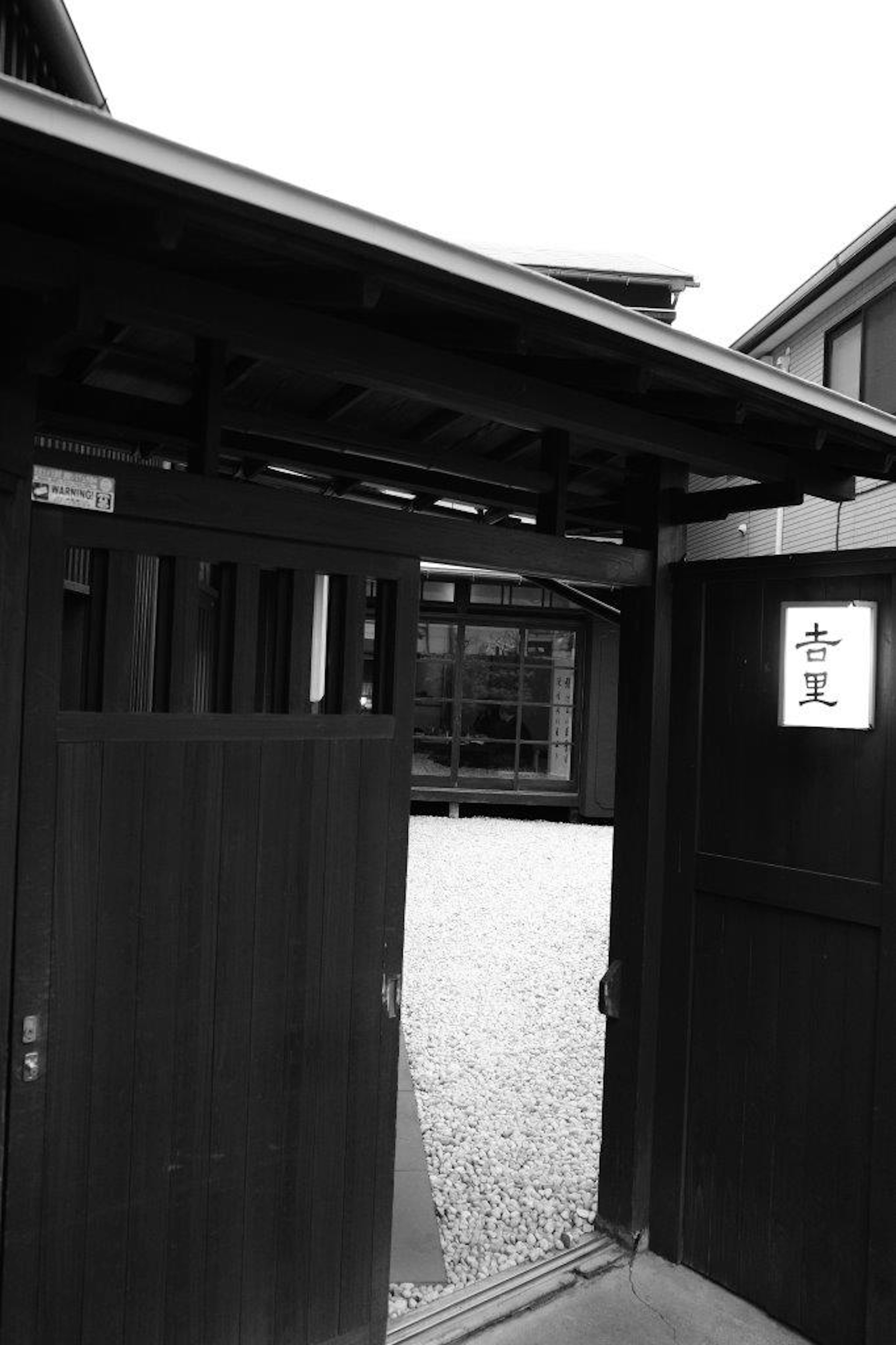 Open wooden gate leading to a traditional Japanese building entrance