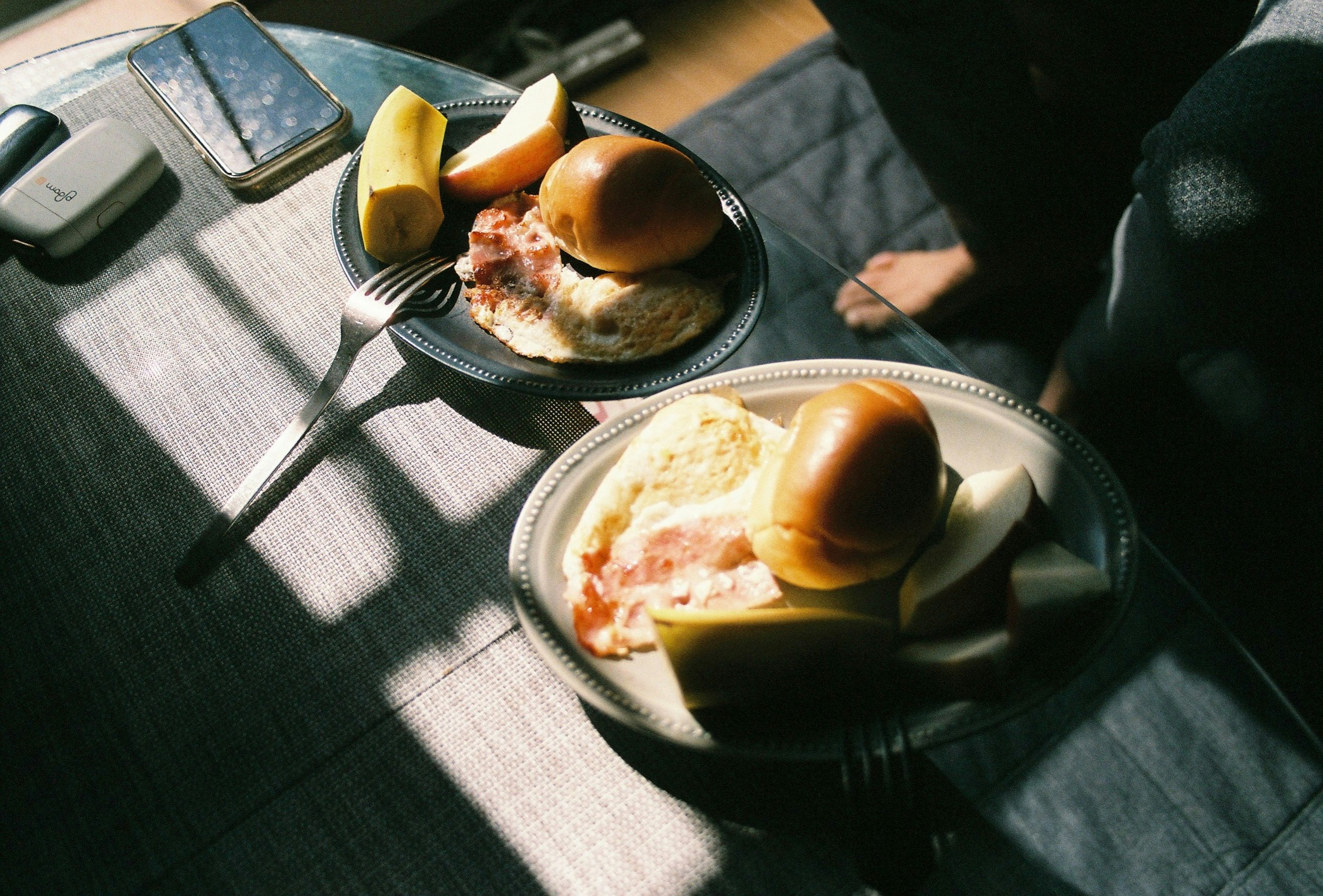 Two plates of breakfast food on a table with light streaming in