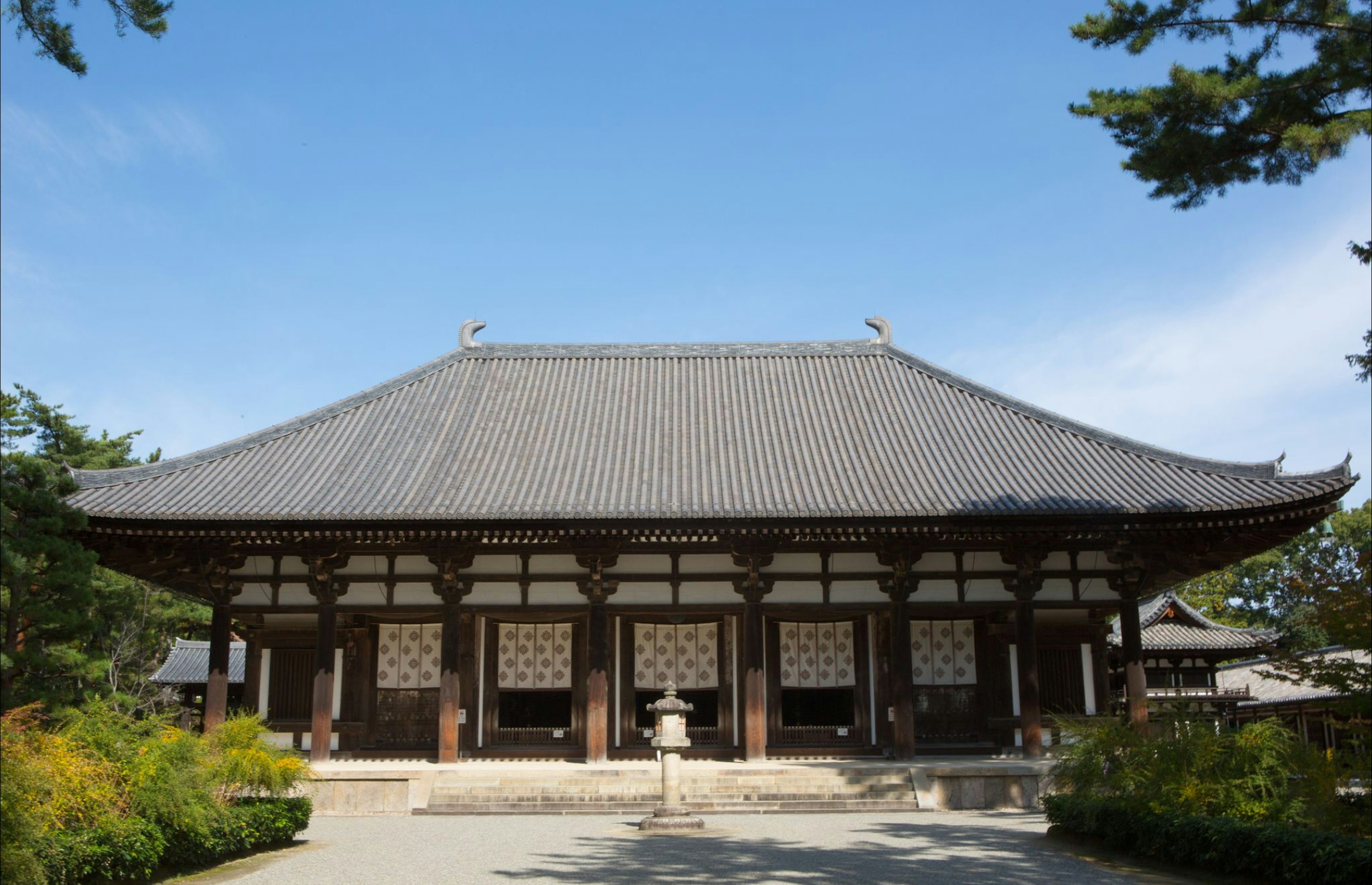 Hermosa fachada de un templo japonés rodeado de jardines exuberantes y cielo azul