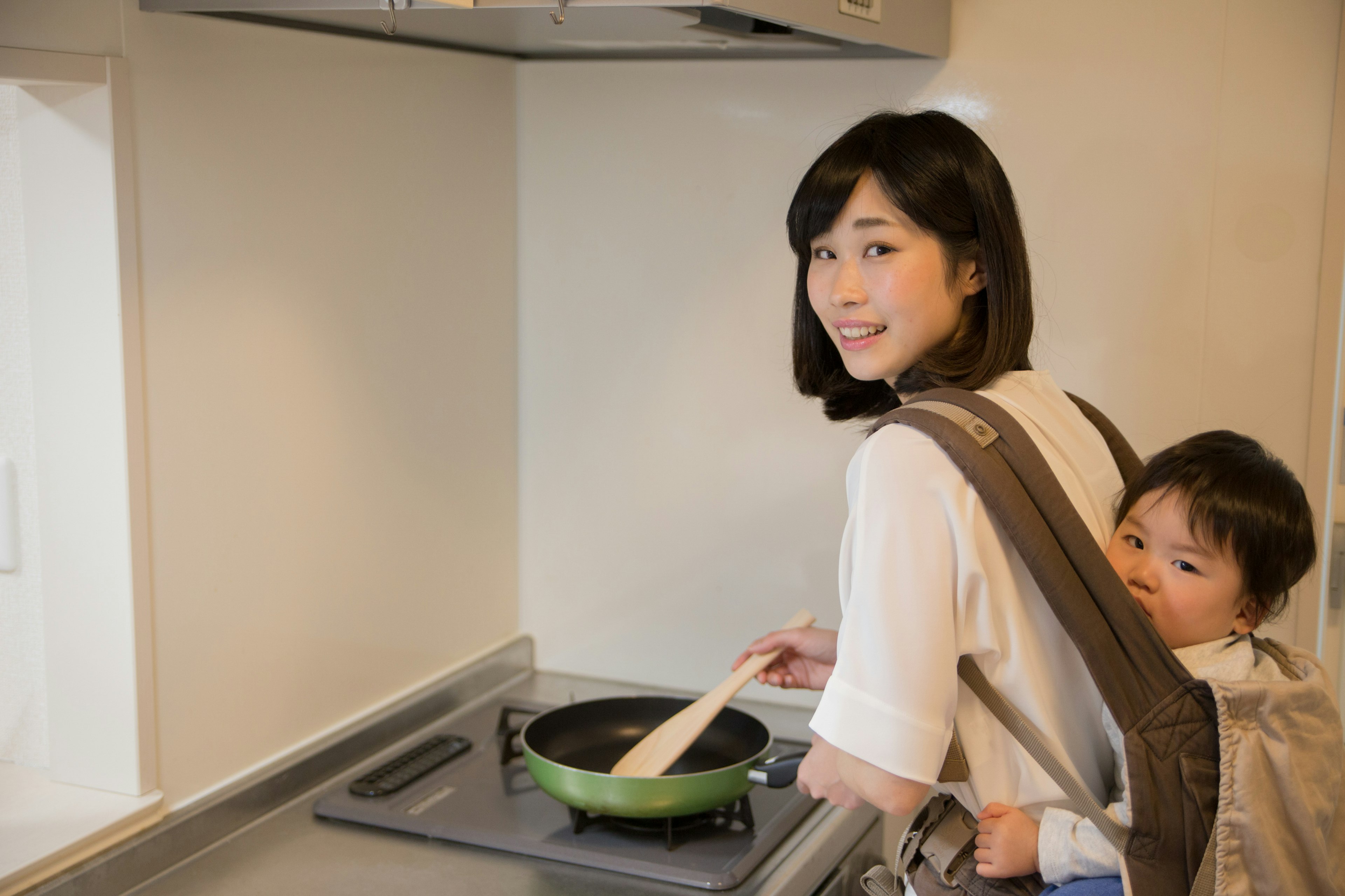 Donna che cucina in una cucina con un bambino in una fascia