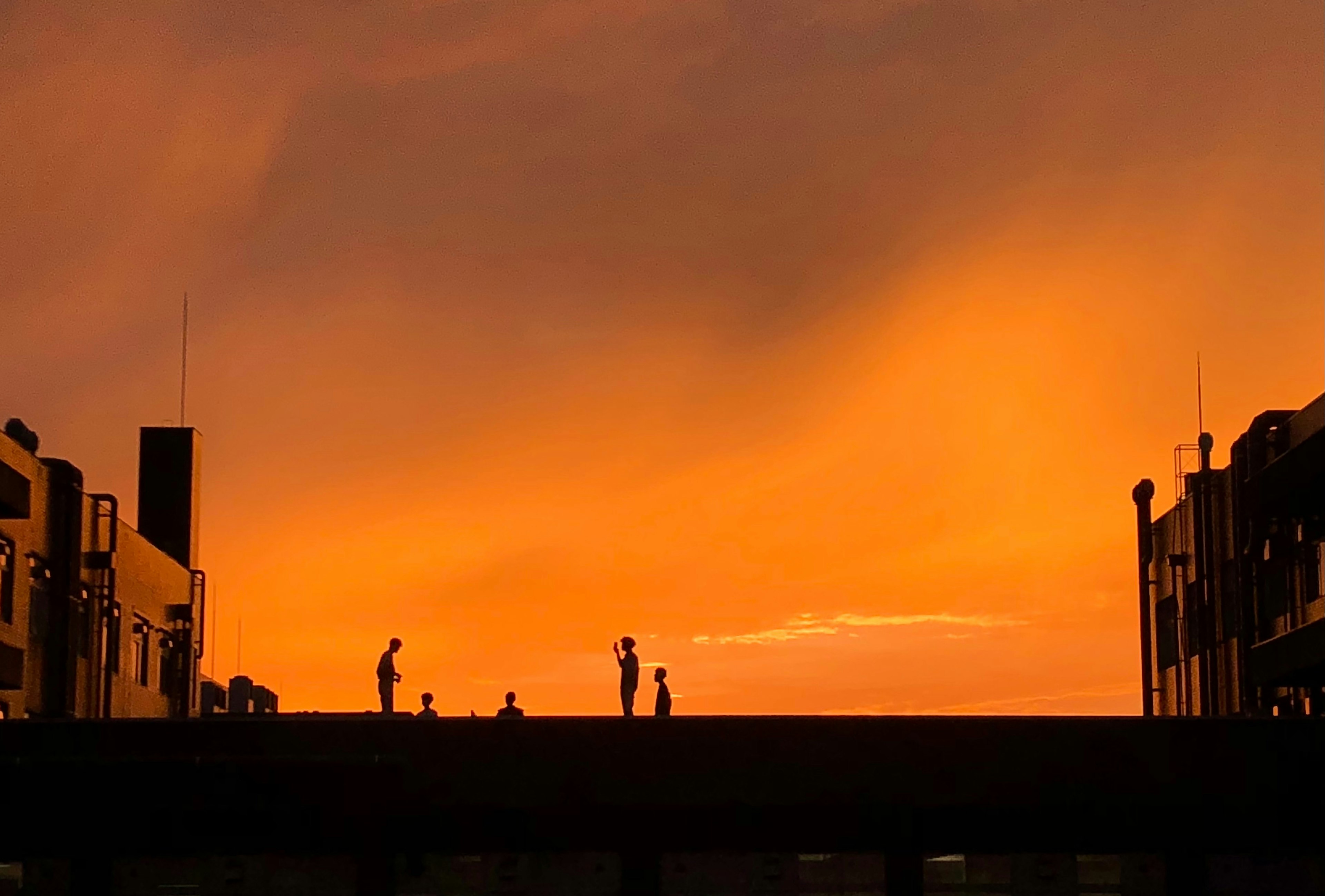 夕焼けの空を背景に人々がシルエットになっている風景