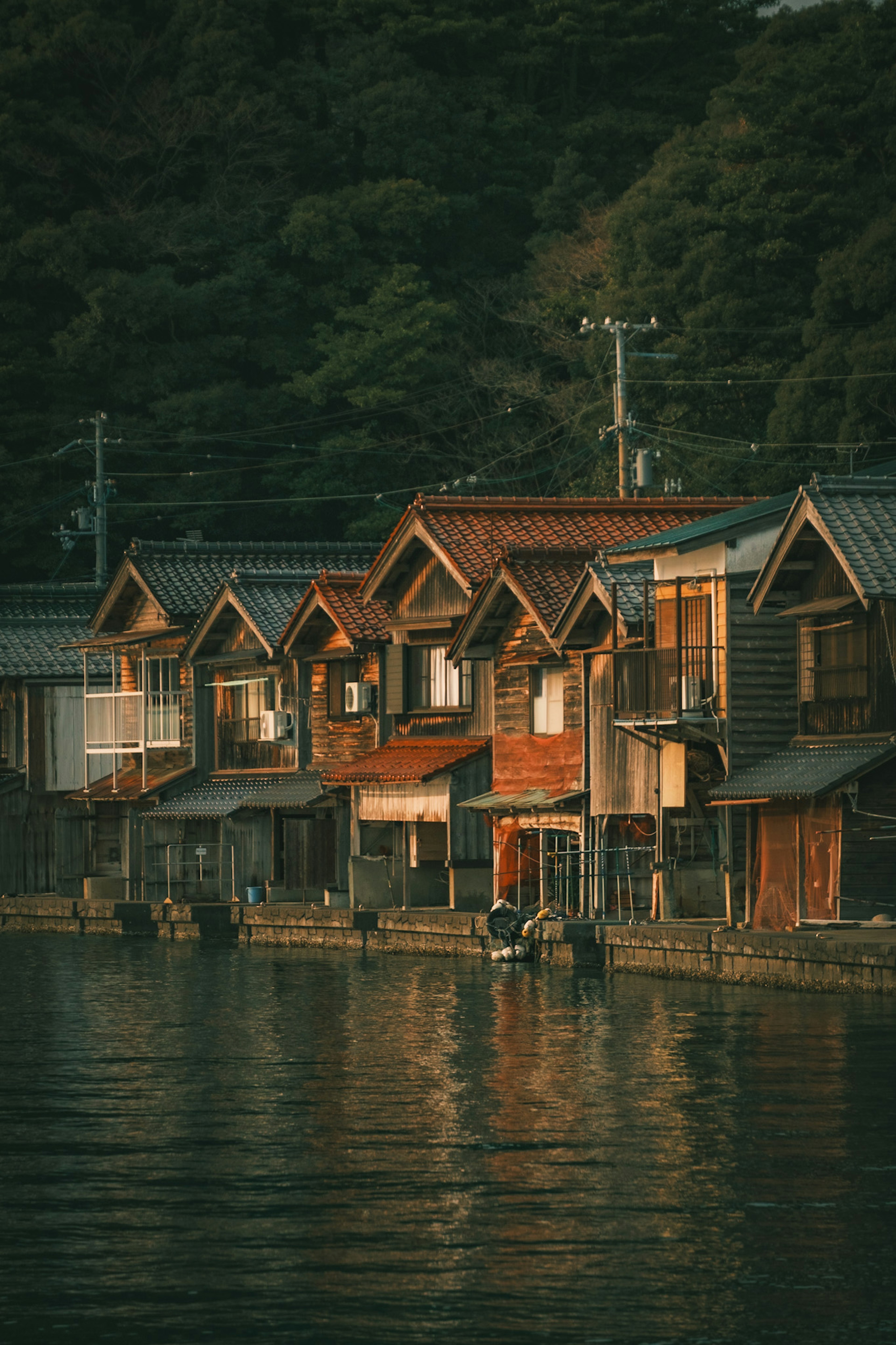 夕暮れ時の水辺に並ぶ伝統的な木造家屋