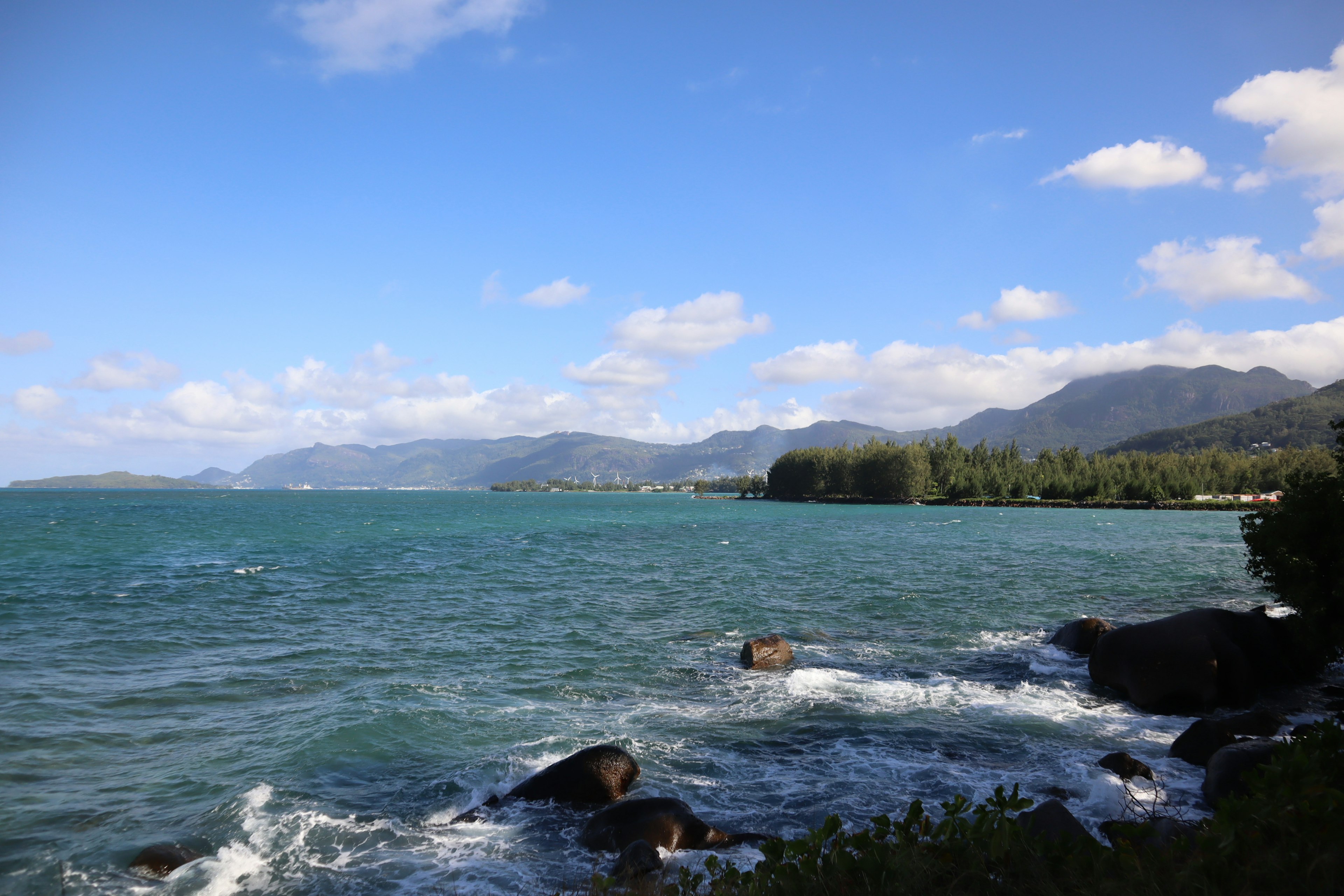 Scenic view of blue ocean waves and mountains under a clear sky