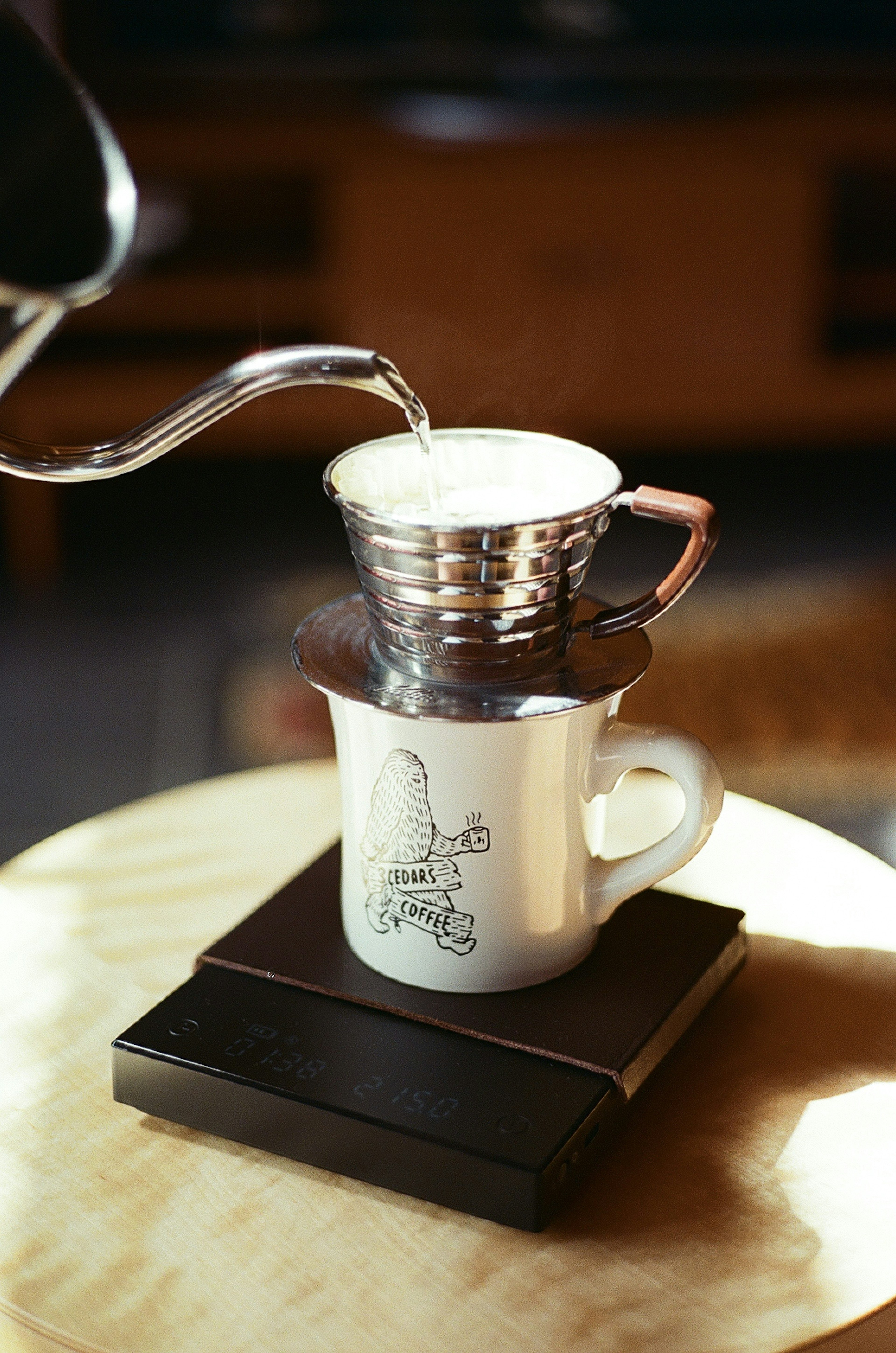 Coffee dripper and cup on a wooden table with a kettle pouring water