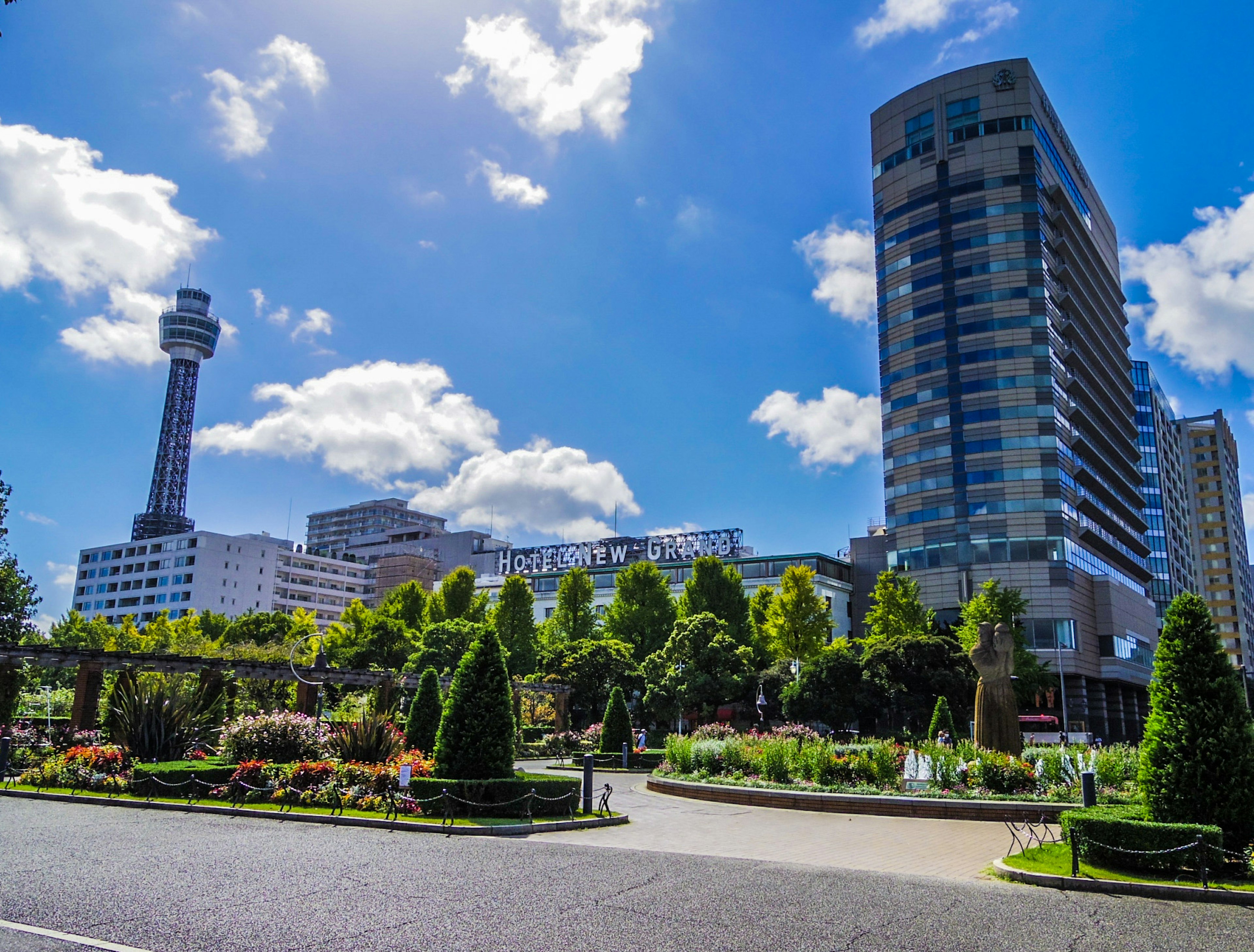 Ein lebhafter Park mit üppigem Grün und modernen Gebäuden unter einem blauen Himmel