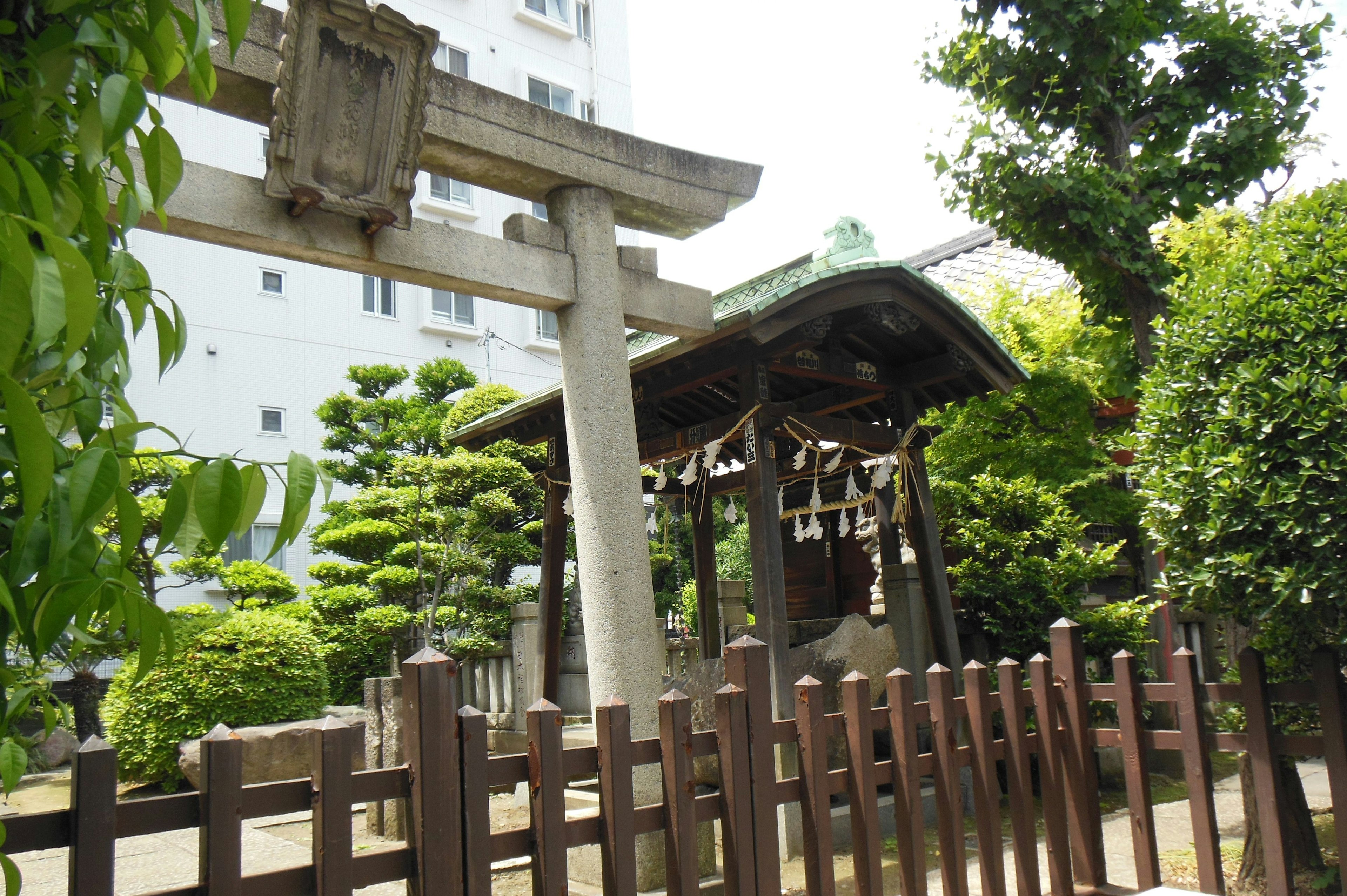 Ansicht eines Torii und eines kleinen Schreins umgeben von üppigem Grün