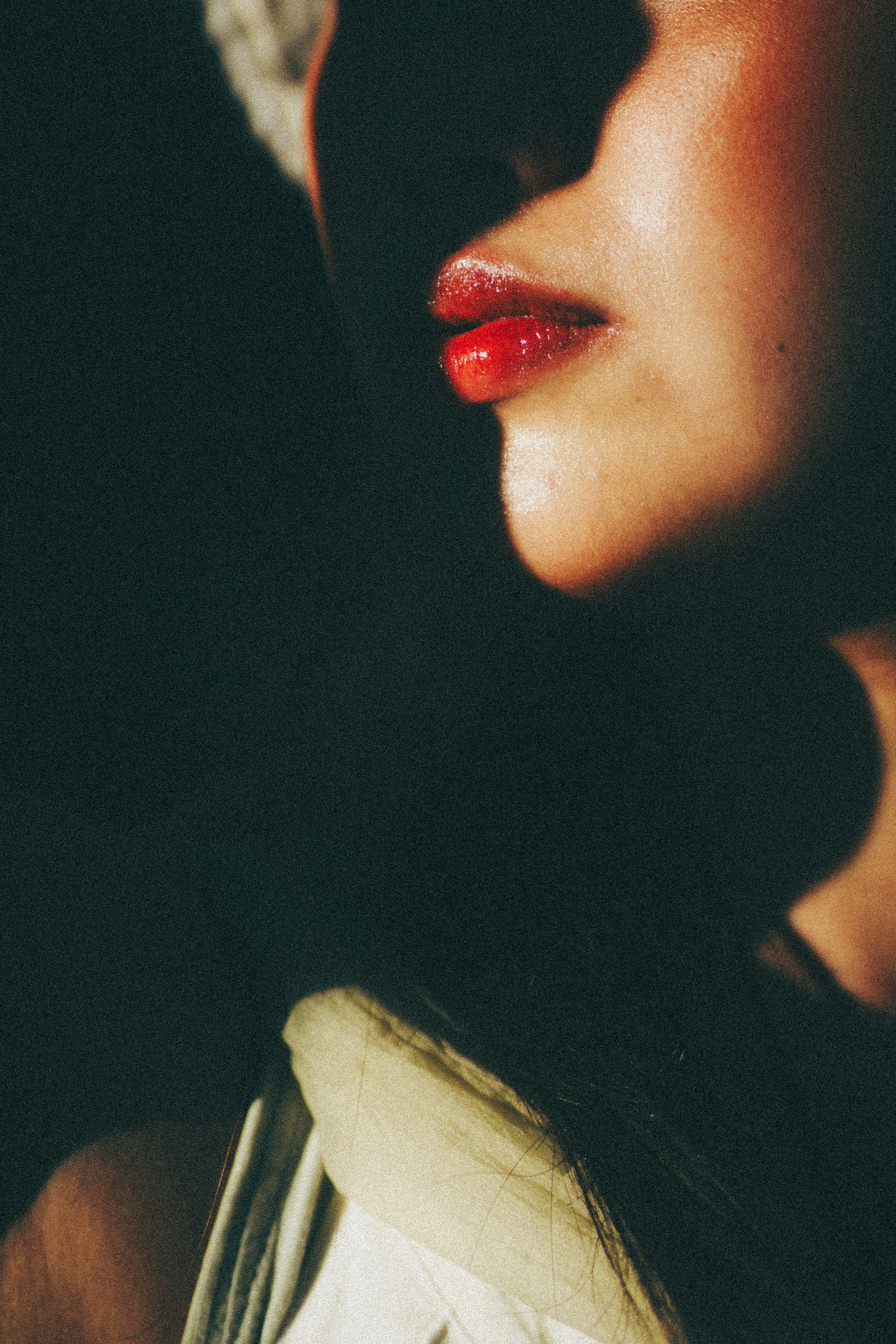 Close-up bibir wanita dengan lipstik merah di latar belakang gelap