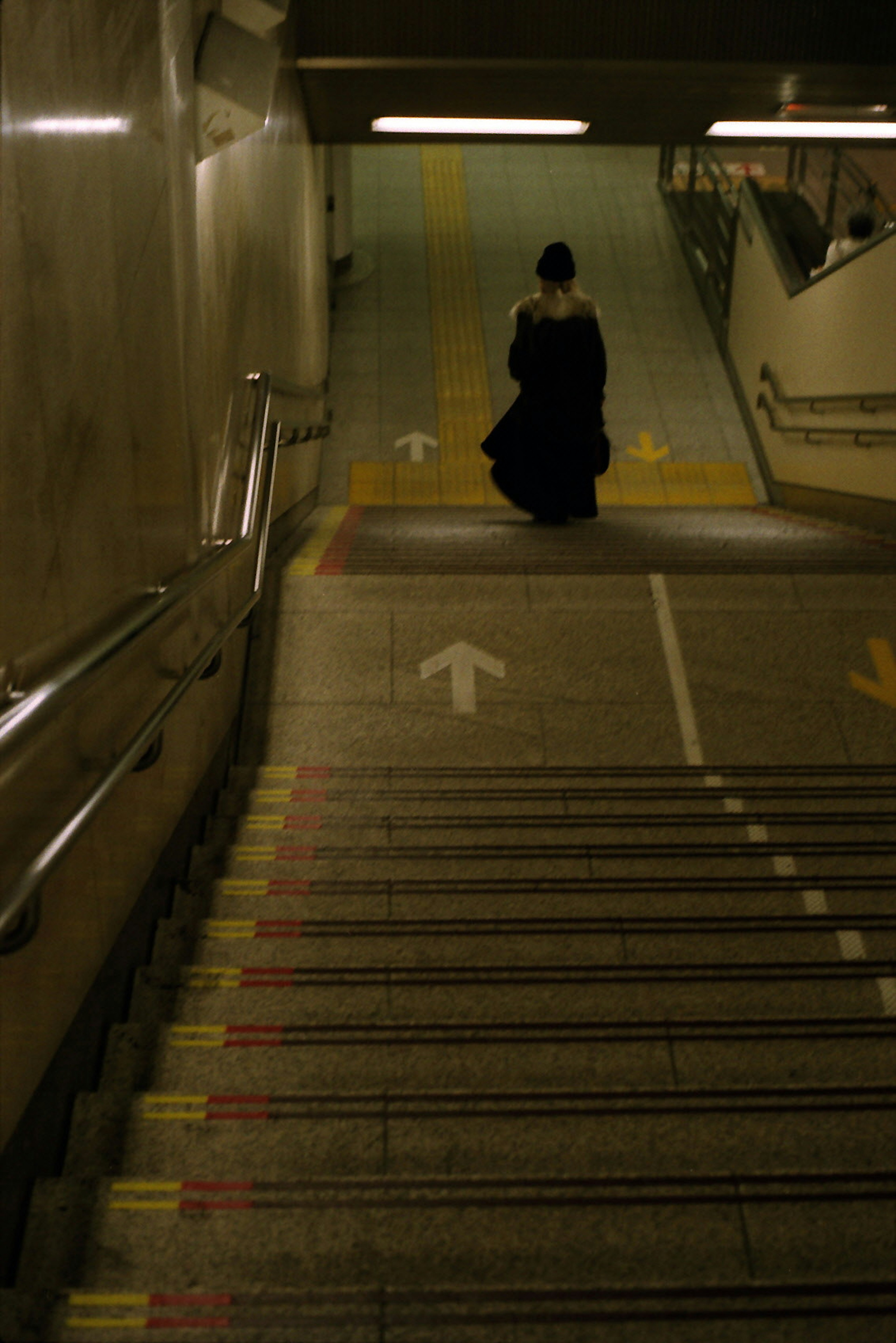 A person in black clothing descending stairs in a quiet scene