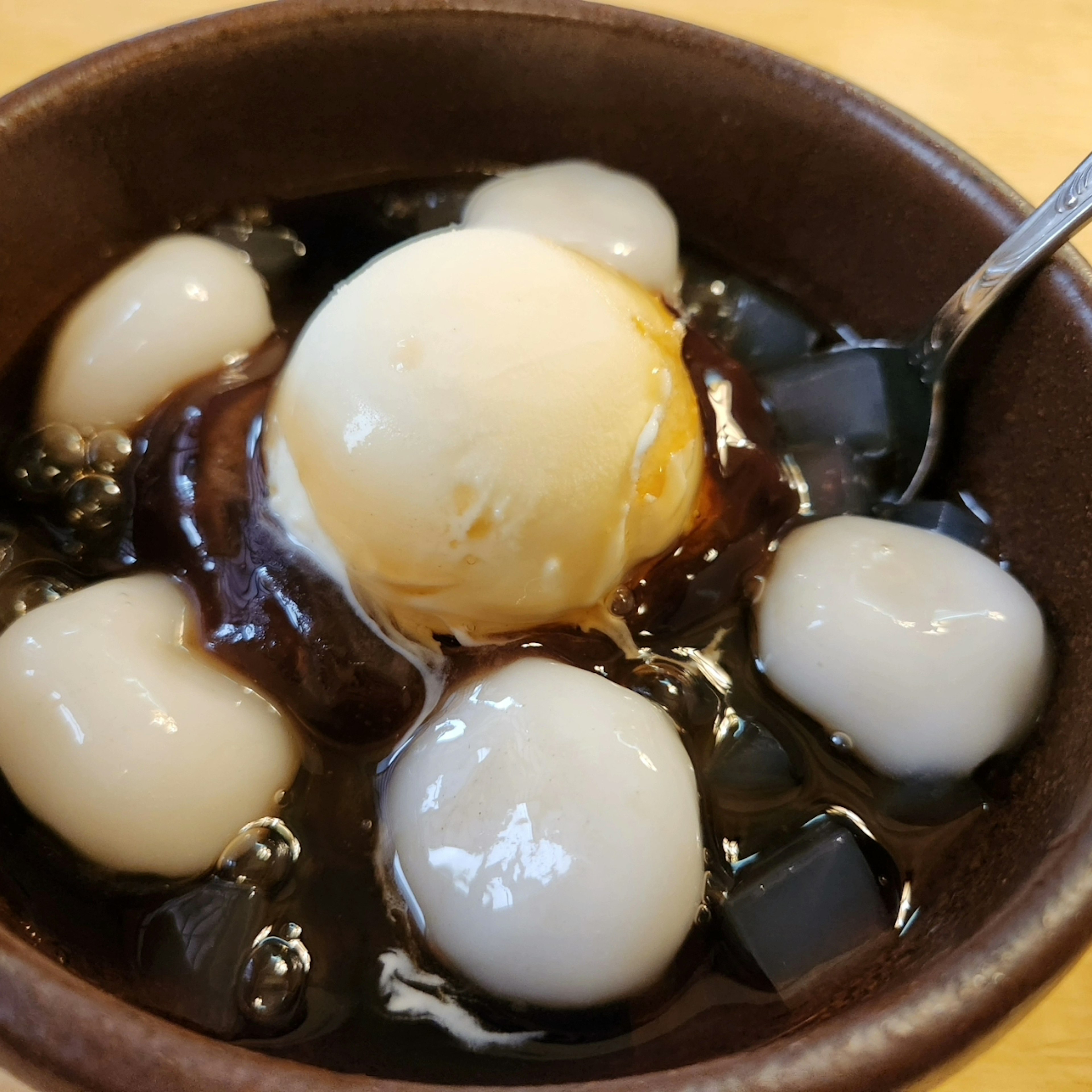 Postre con helado y bolas de mochi en jarabe dulce