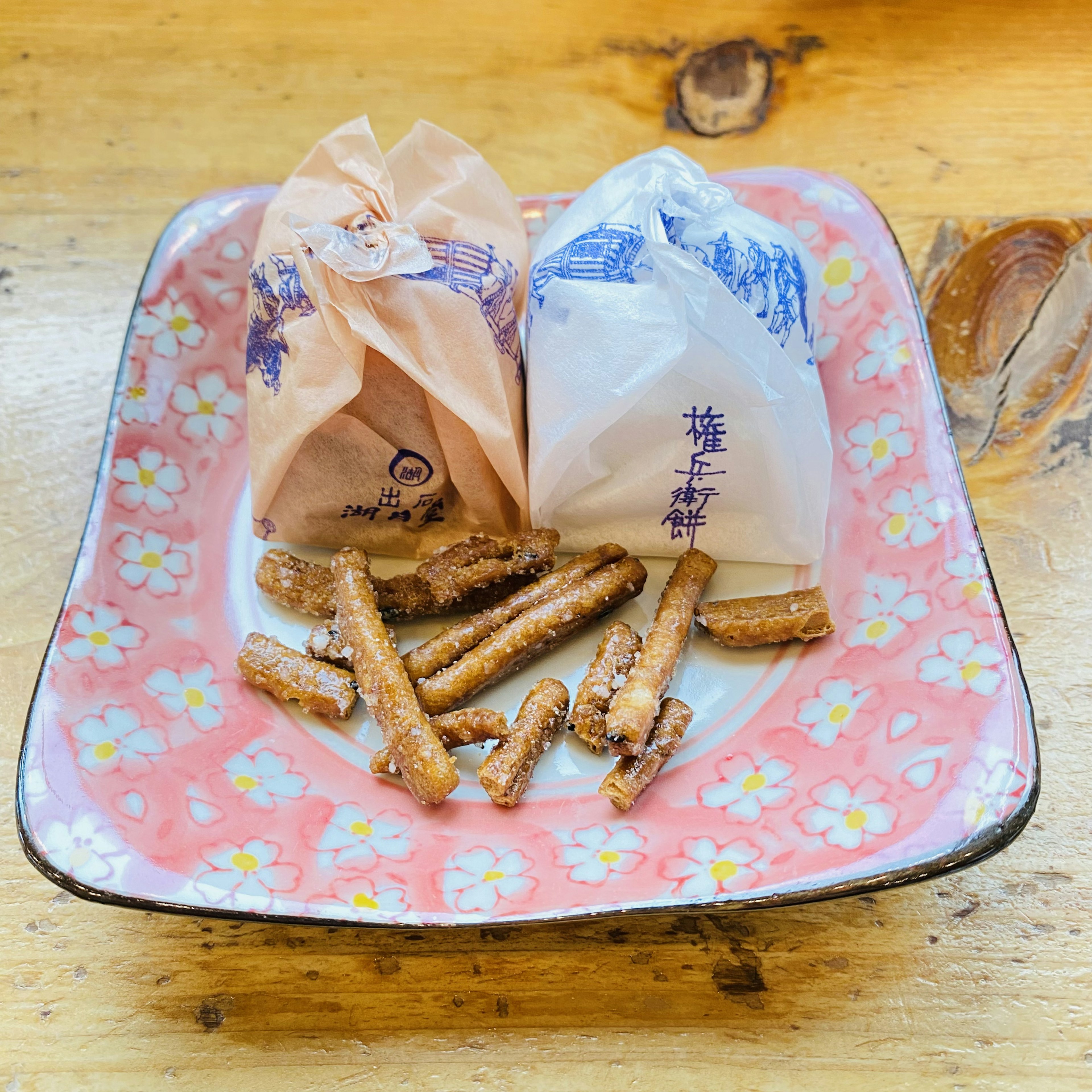 A decorative plate with two wrapped snacks and long crunchy sticks