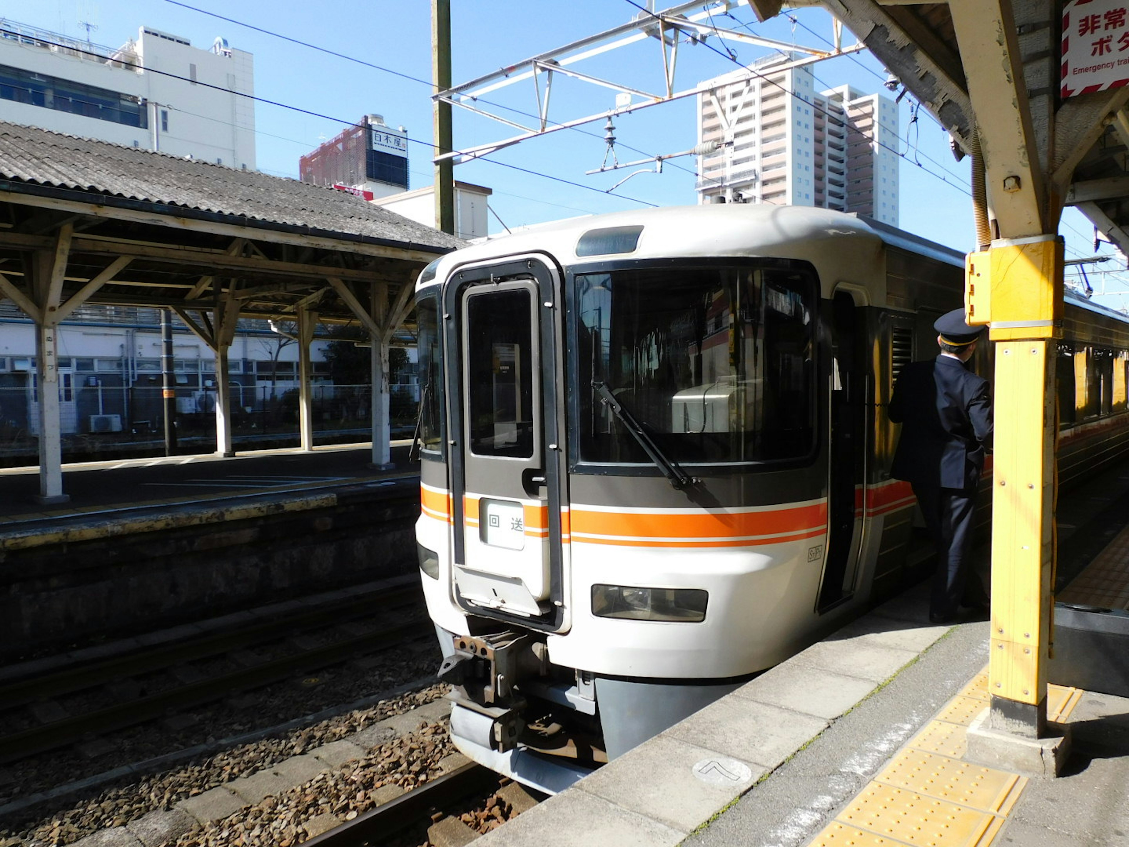 駅に停車中の白い電車と周囲の建物