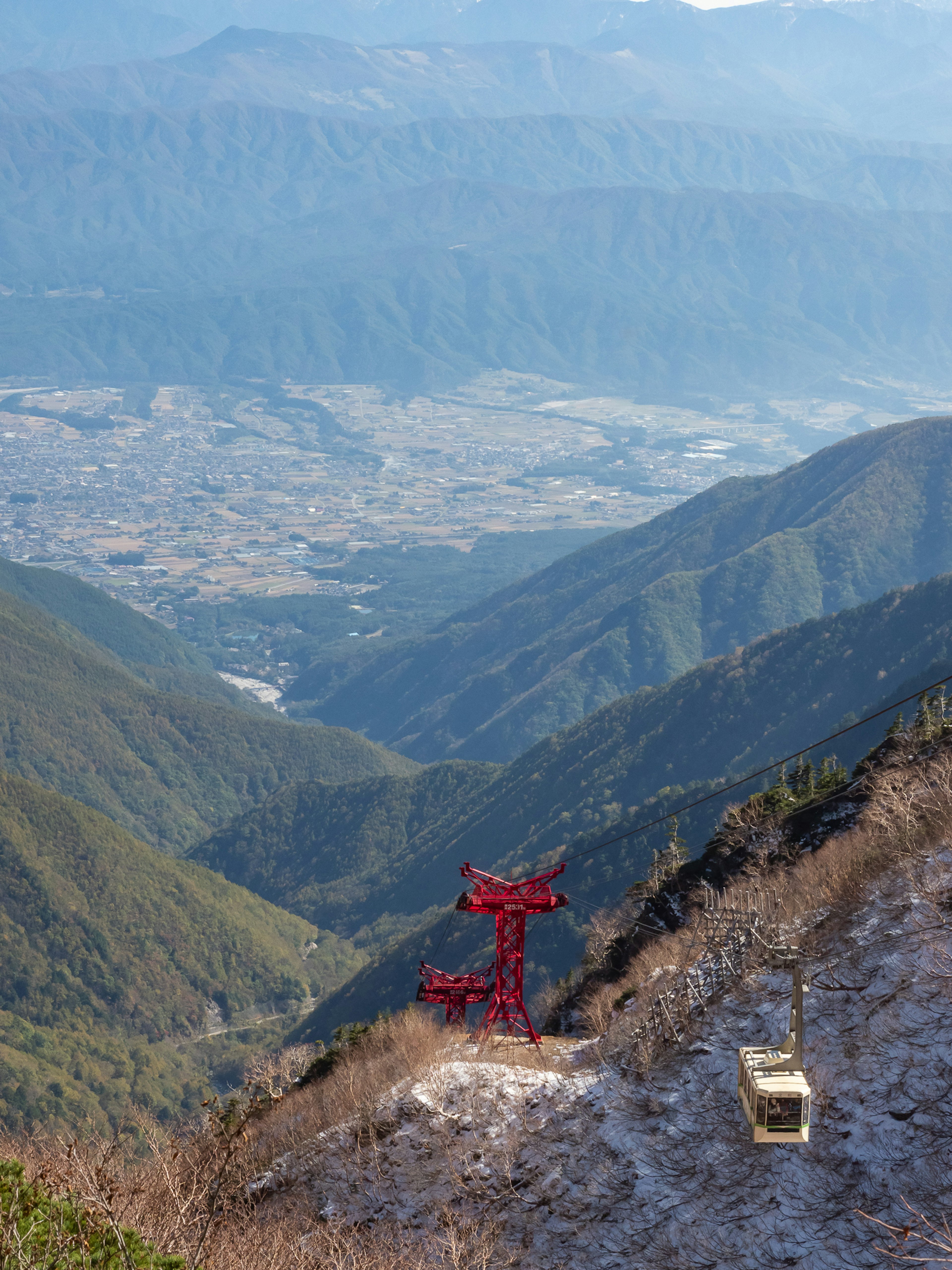 Vue pittoresque depuis une montagne avec un support de téléphérique rouge