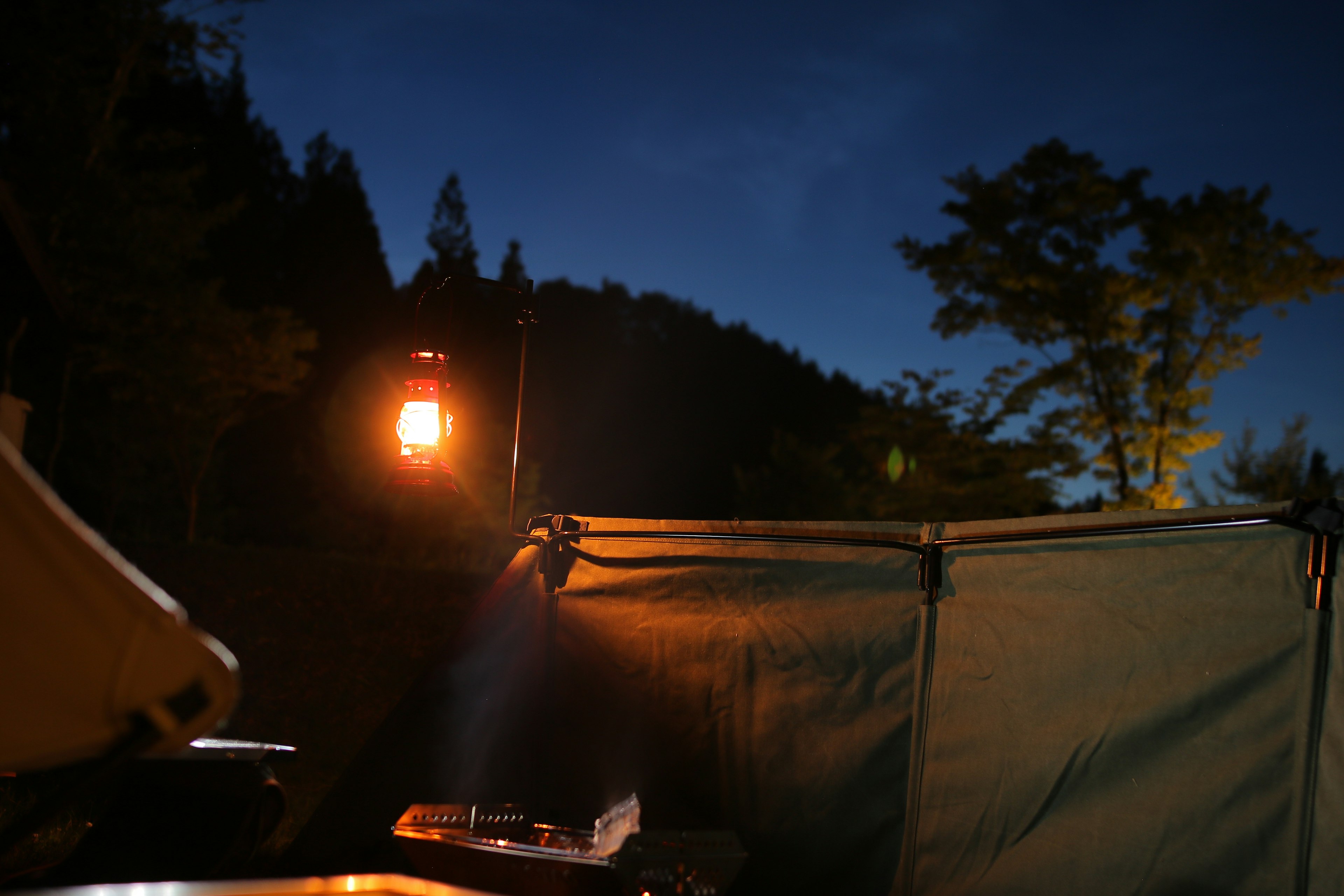 Lantern illuminating a campsite at night with a tent