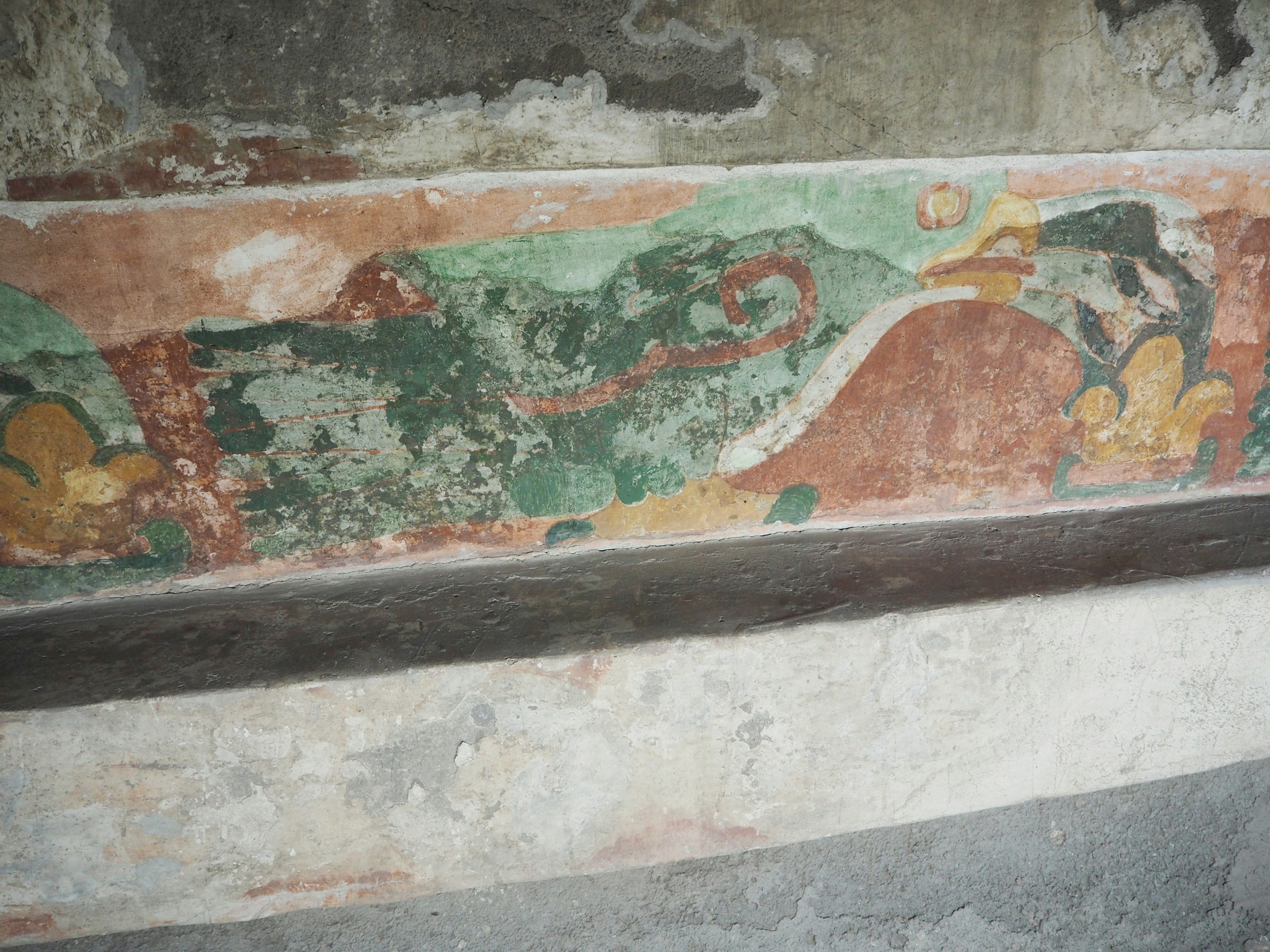 Fresco antiguo que presenta una criatura verde en una pared