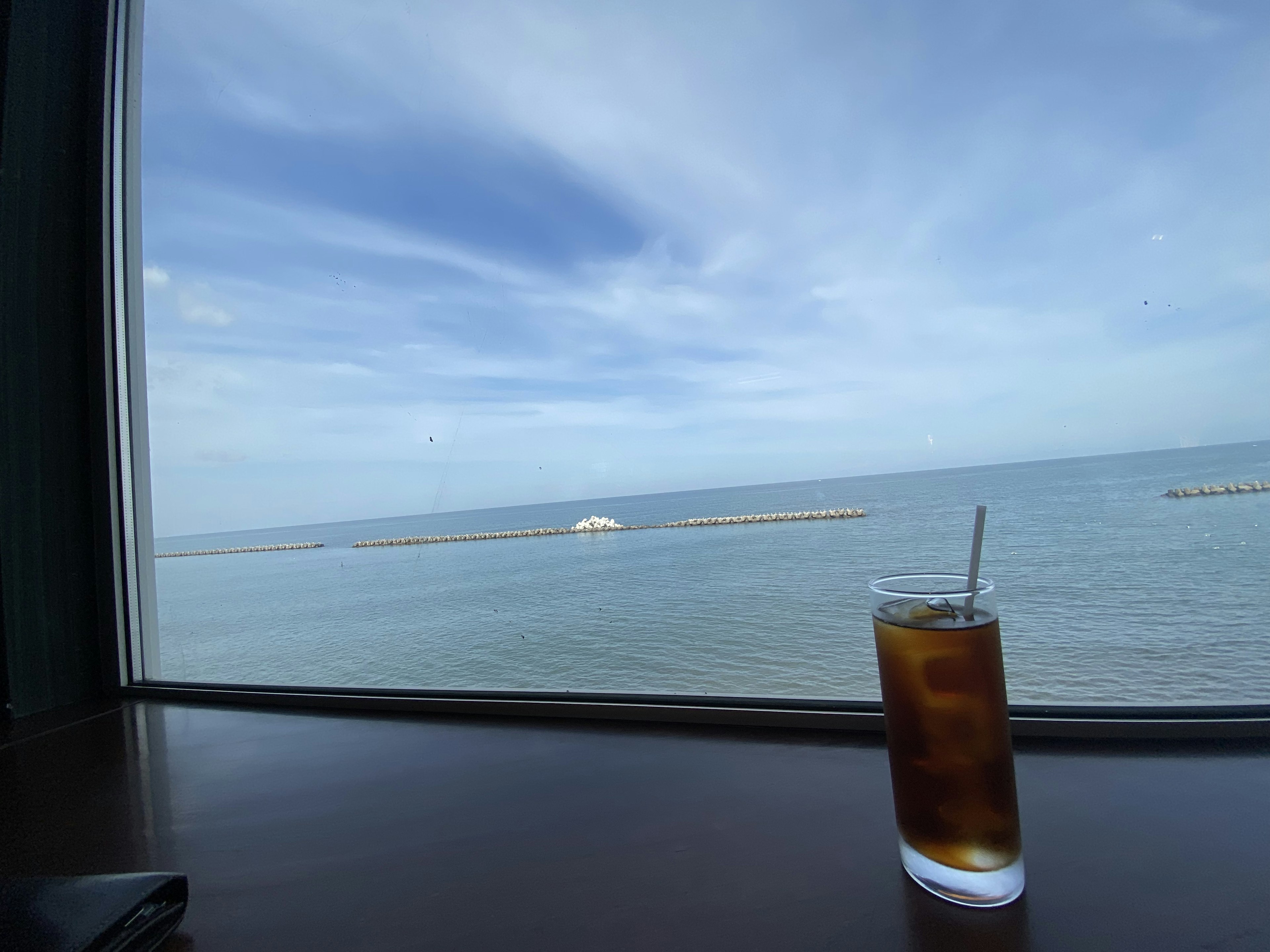 海の景色とアイスティーの飲み物がある窓辺の風景